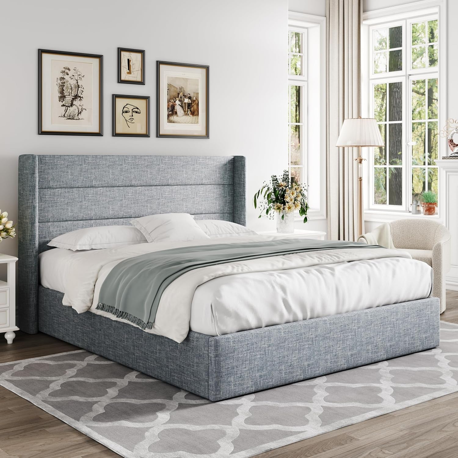 Angled bedroom view showing the gray fabric storage bed with bedding, side tables and a windowed corner.
