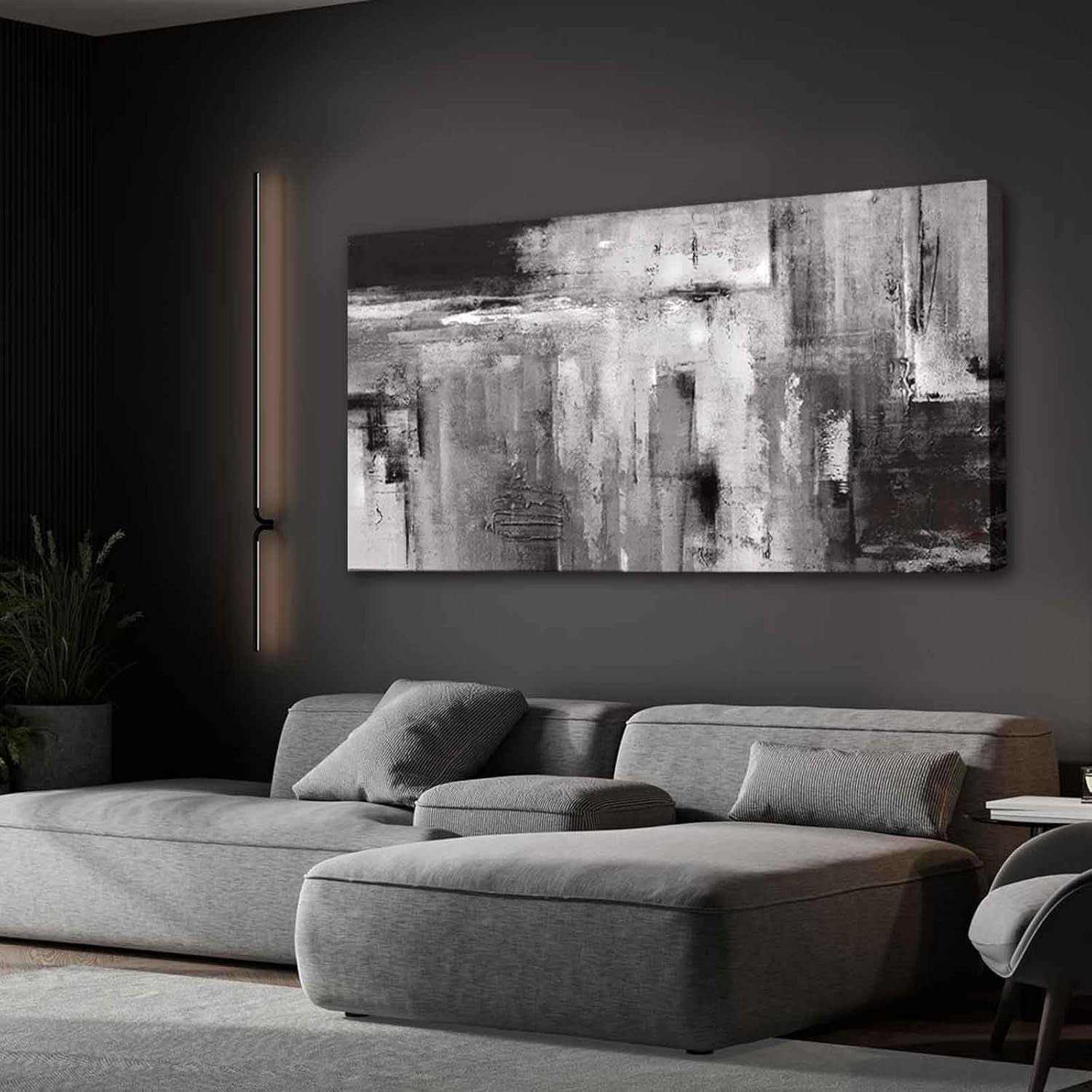 Moody lounge with charcoal walls and a large monochrome abstract canvas illuminated by a vertical wall light