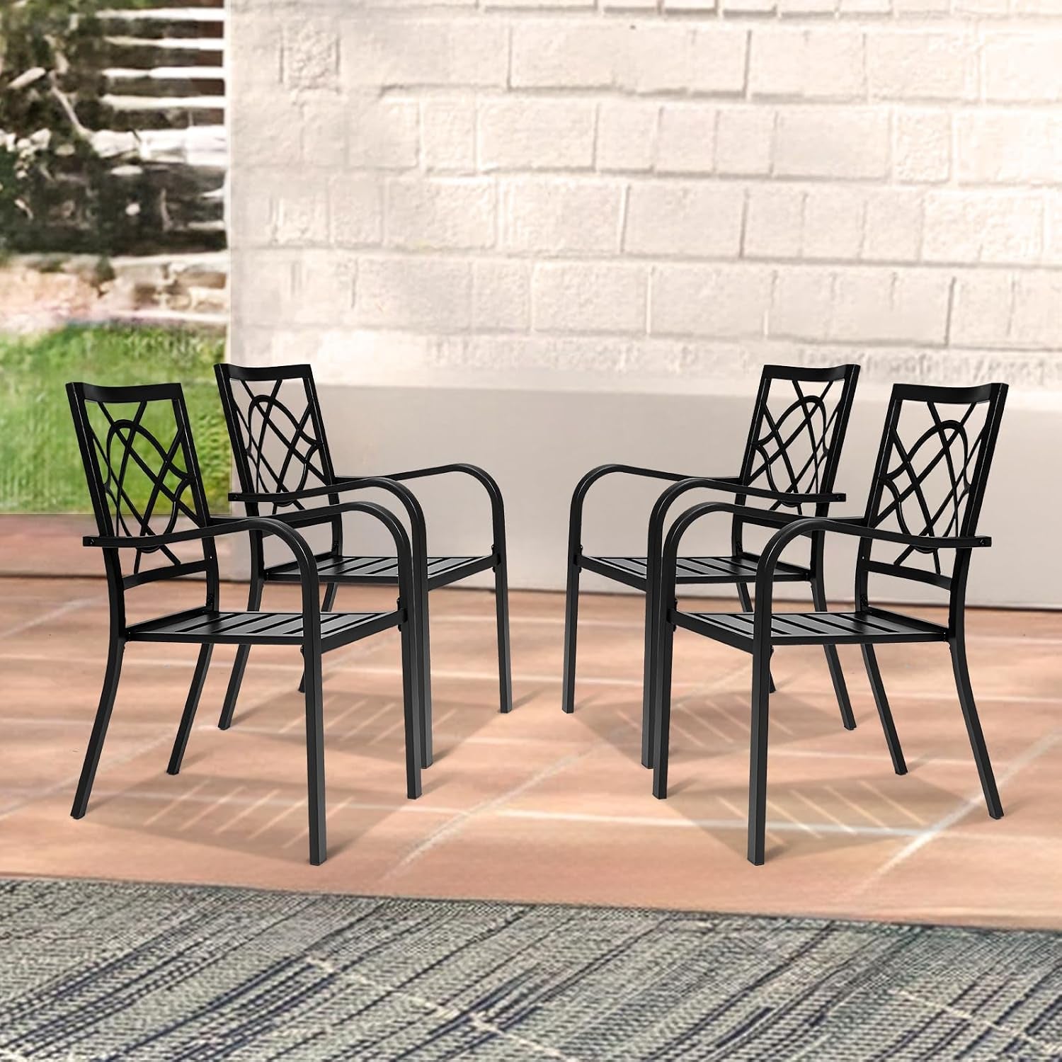 Four black metal chairs arranged in a loose square on a terracotta patio against a light brick wall.