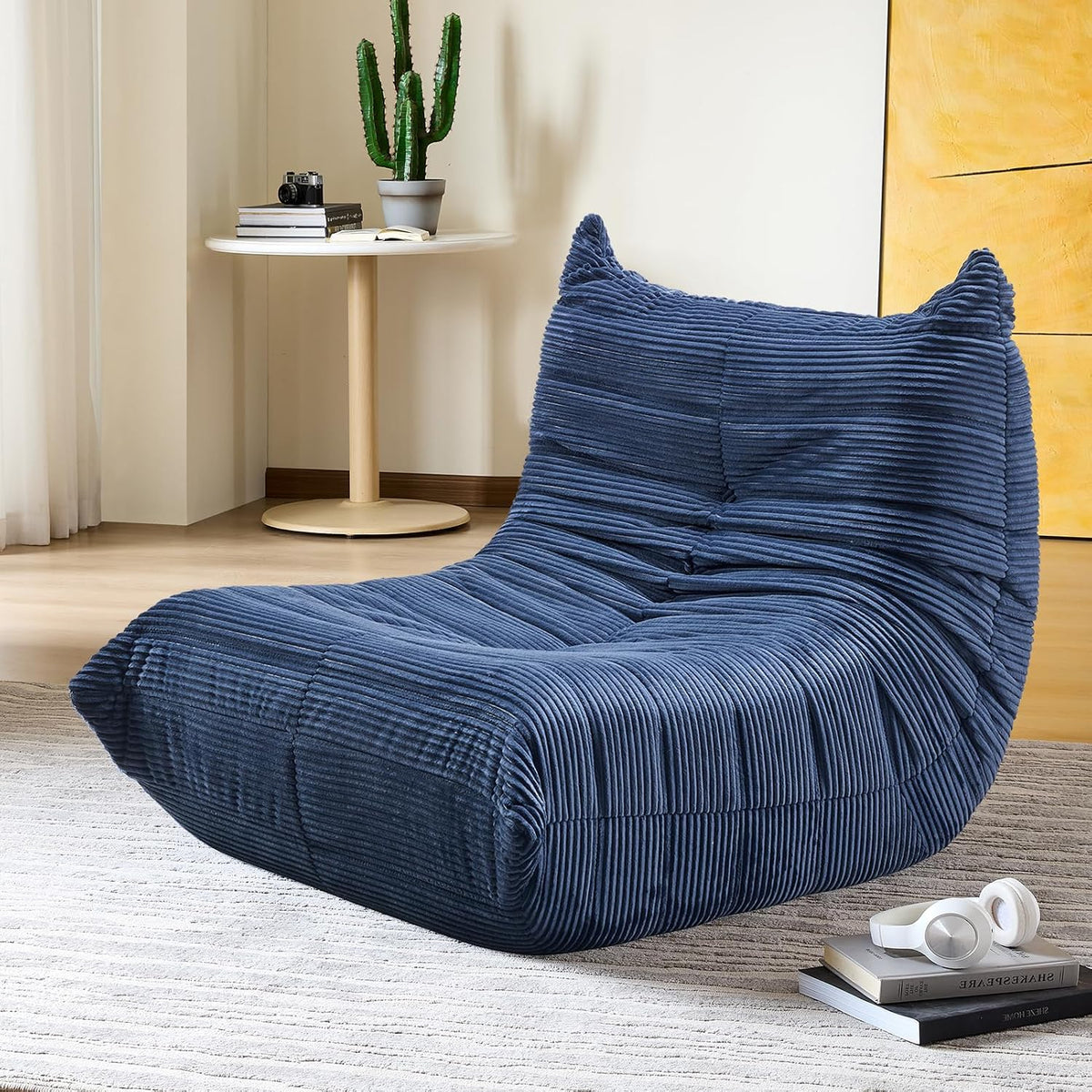 Blue teddy velvet lounger shown in a living room setting with a round side table and rug