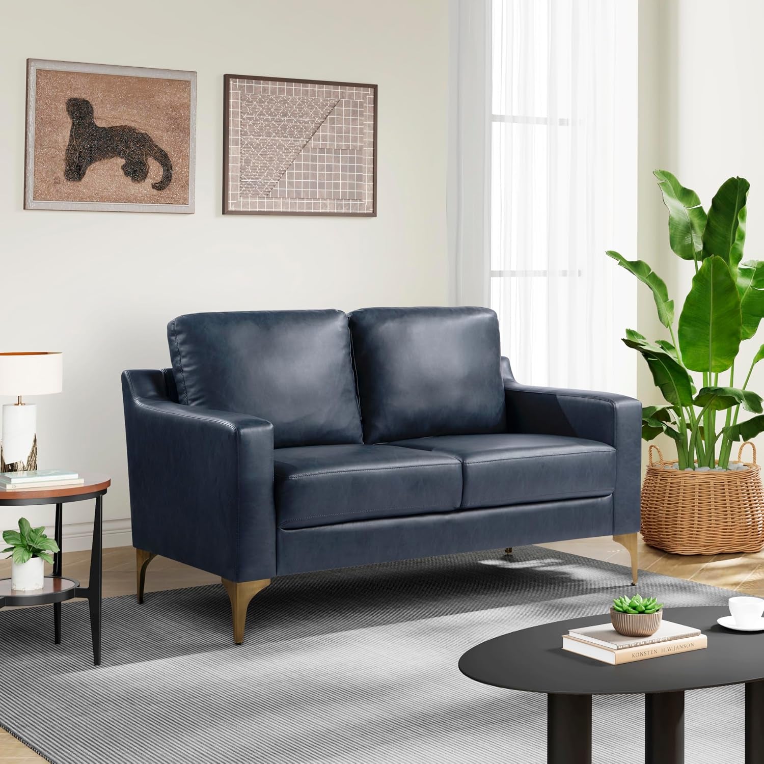 Two-seat navy faux-leather sofa in a living room with artwork and plants.