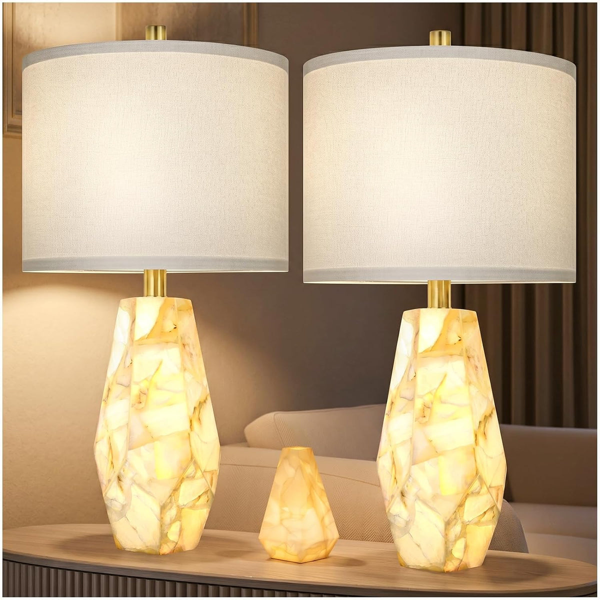 Two glowing alabaster lamps with a small matching nightlight between them on a wood console, sofa visible behind.