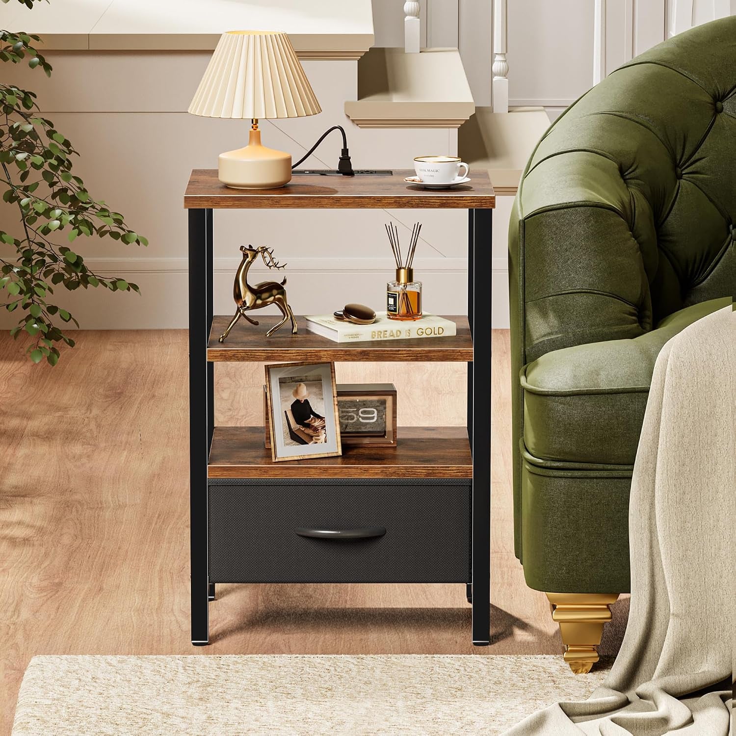 Front view of the three-tier nightstand with closed fabric drawer placed beside a green upholstered sofa.