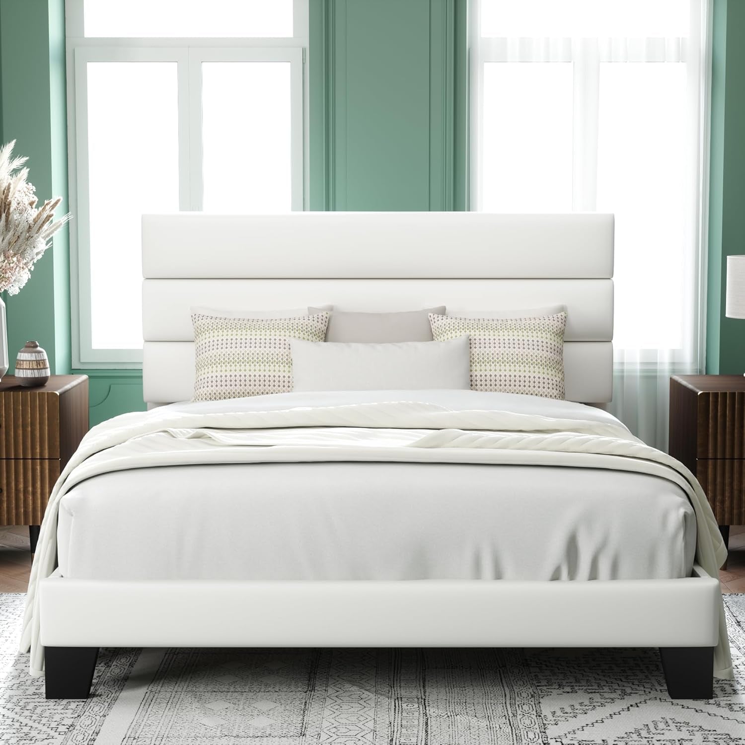 Front view of a white upholstered bed with a three-panel headboard against a green accent wall.
