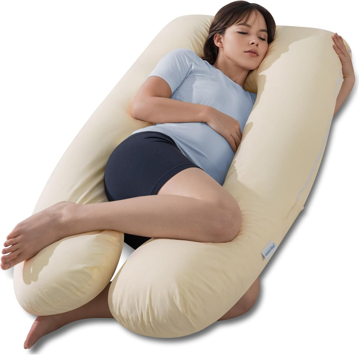High-angle shot of a woman lying in a pale yellow U-shaped maternity pillow with knees bent