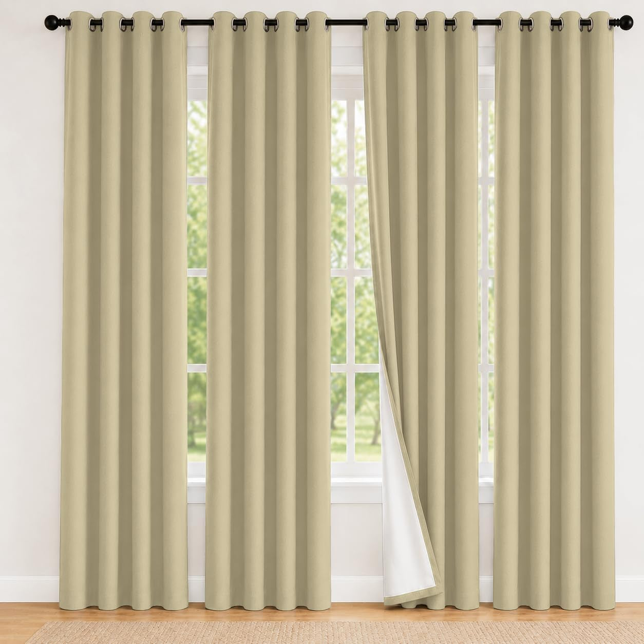 Full-height beige grommet curtains hung on a black rod with one panel folded to show white backing