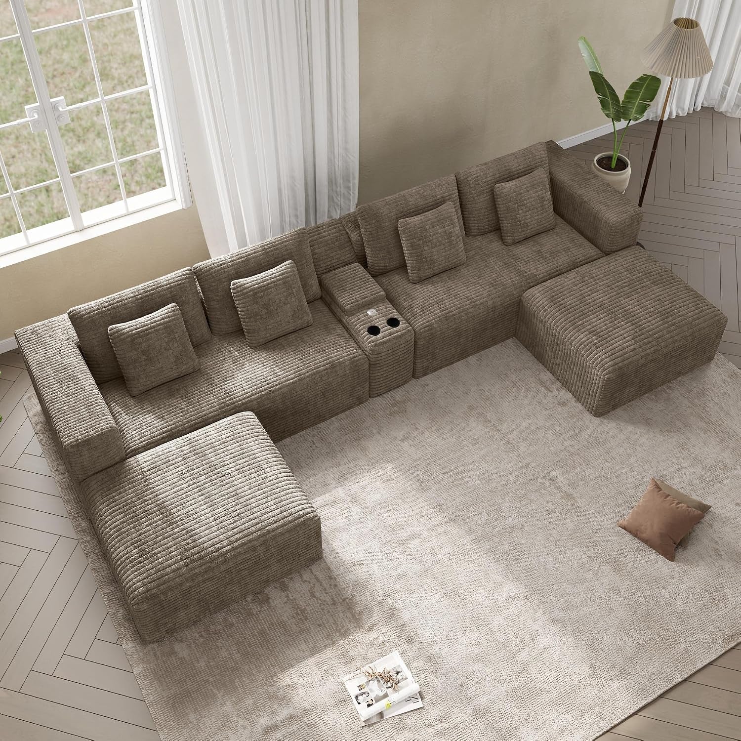 Overhead view of a large U-shaped brown corduroy sectional with a center console and cup holders on a pale rug.