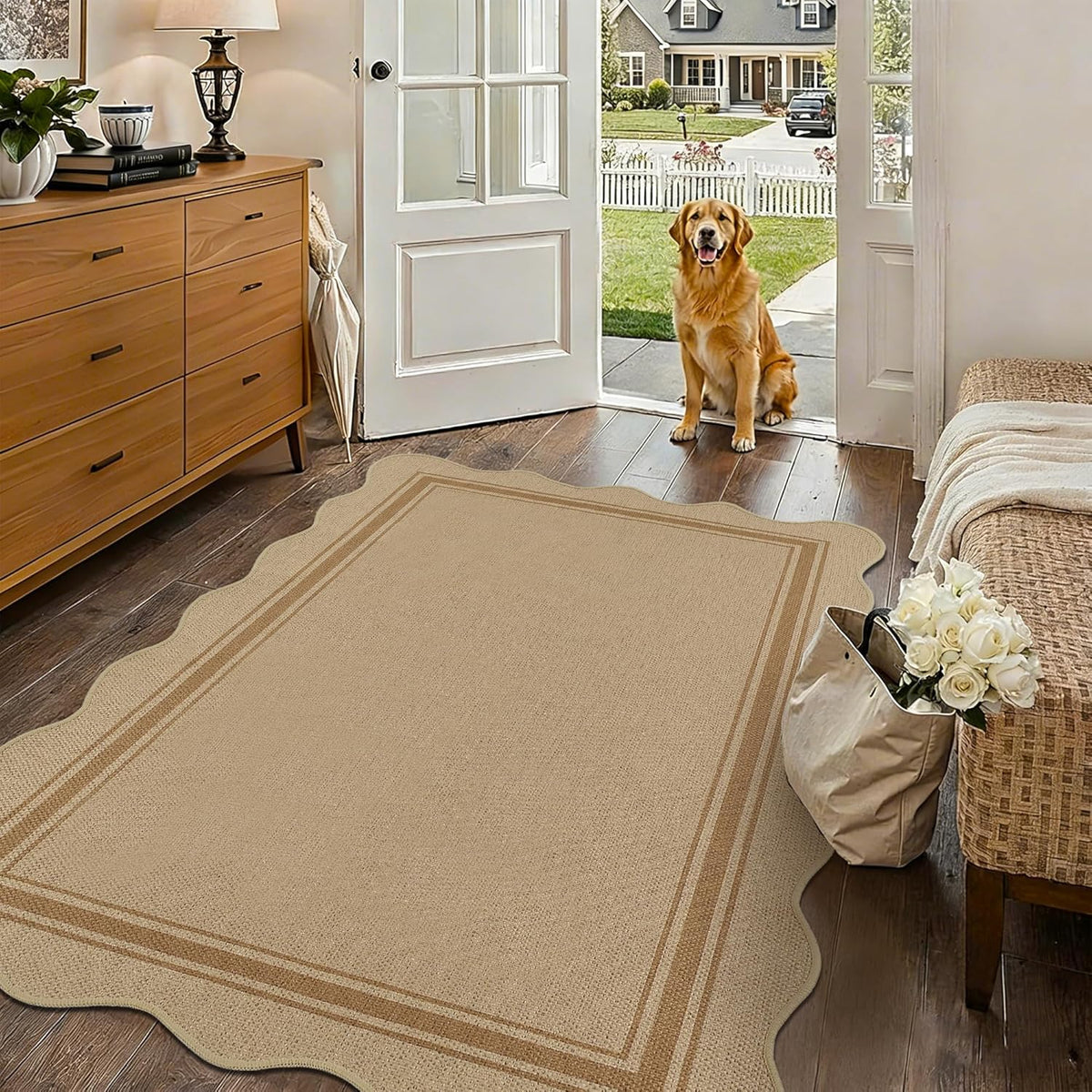 Entryway with open door and golden retriever, beige scalloped rug on wood floor near dresser and tote bag.