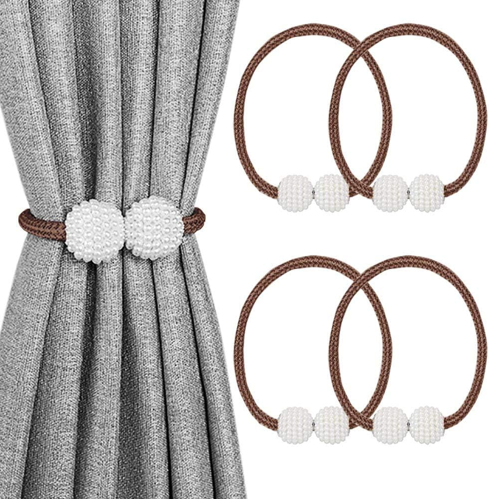 Close view of a gray curtain secured by a brown braided magnetic tieback with two white beaded balls and three extra loops.