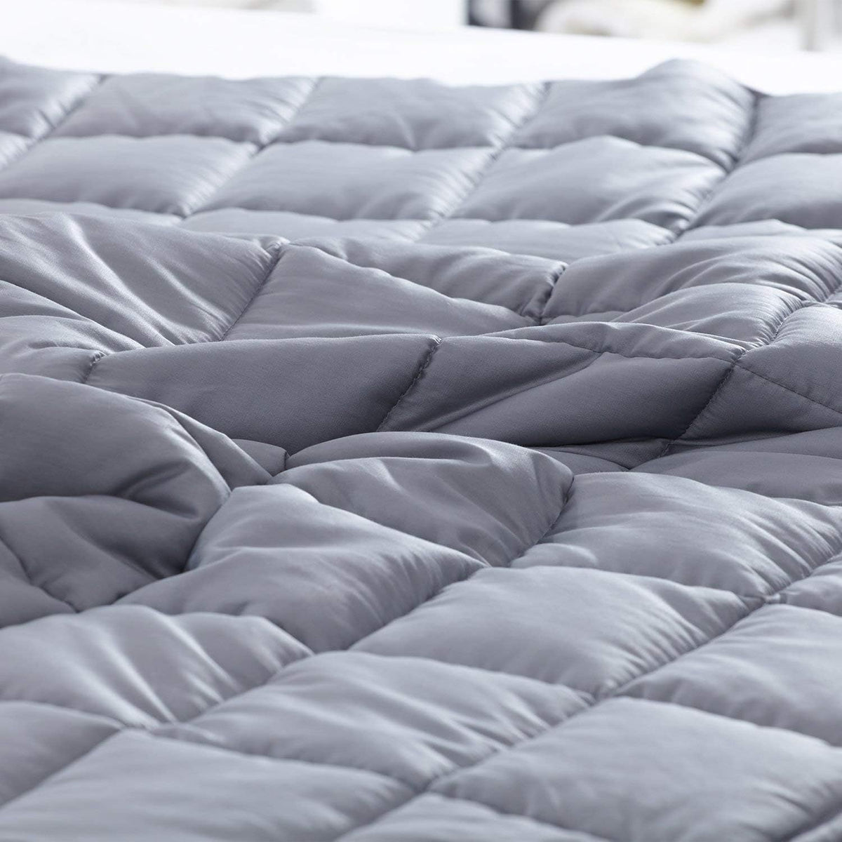 Close-up of light gray blanket showing square quilted pockets and soft textured surface