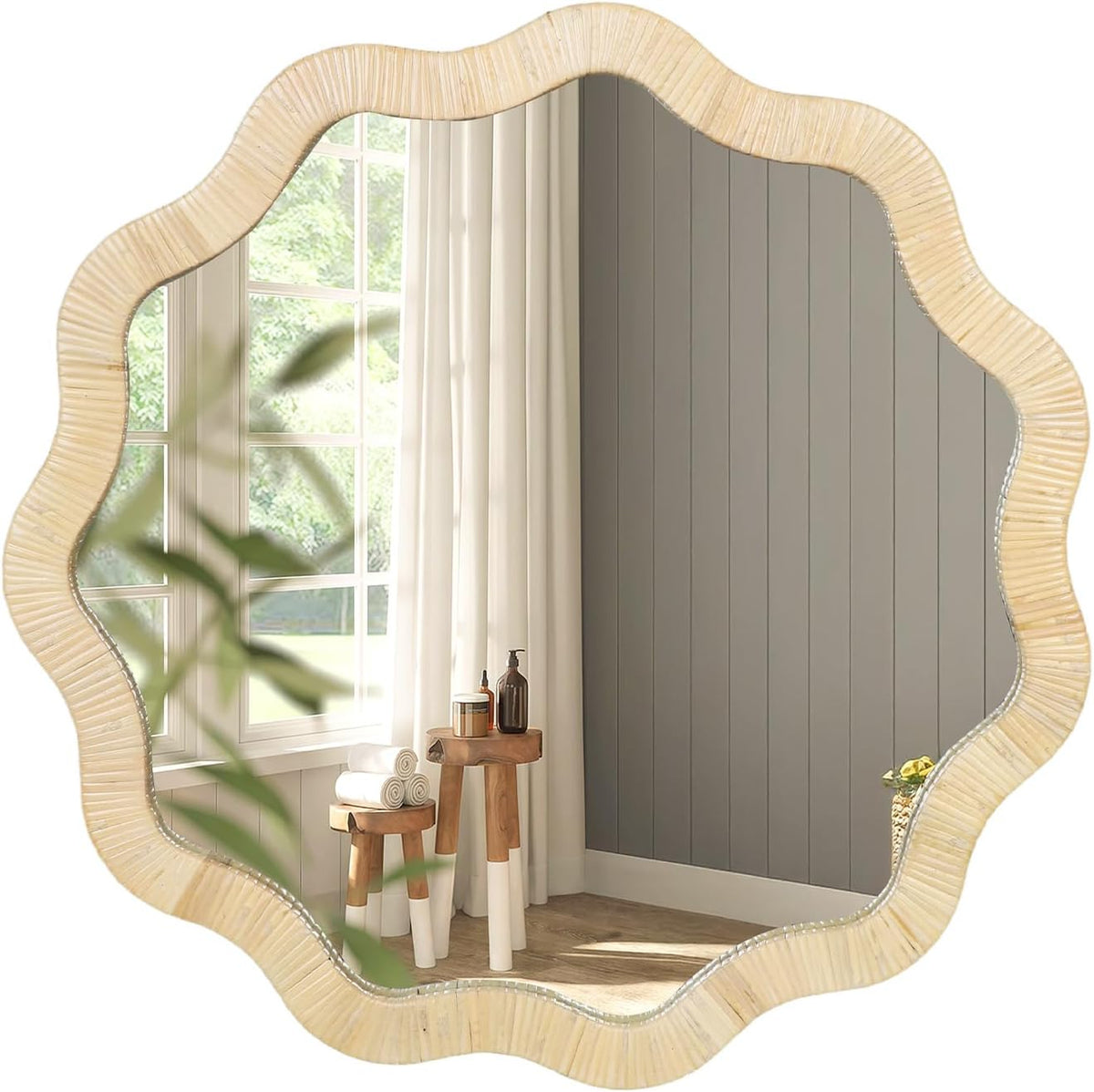 Scalloped natural rattan mirror reflecting white curtains, gray vertical-paneled wall and a small wooden side table with