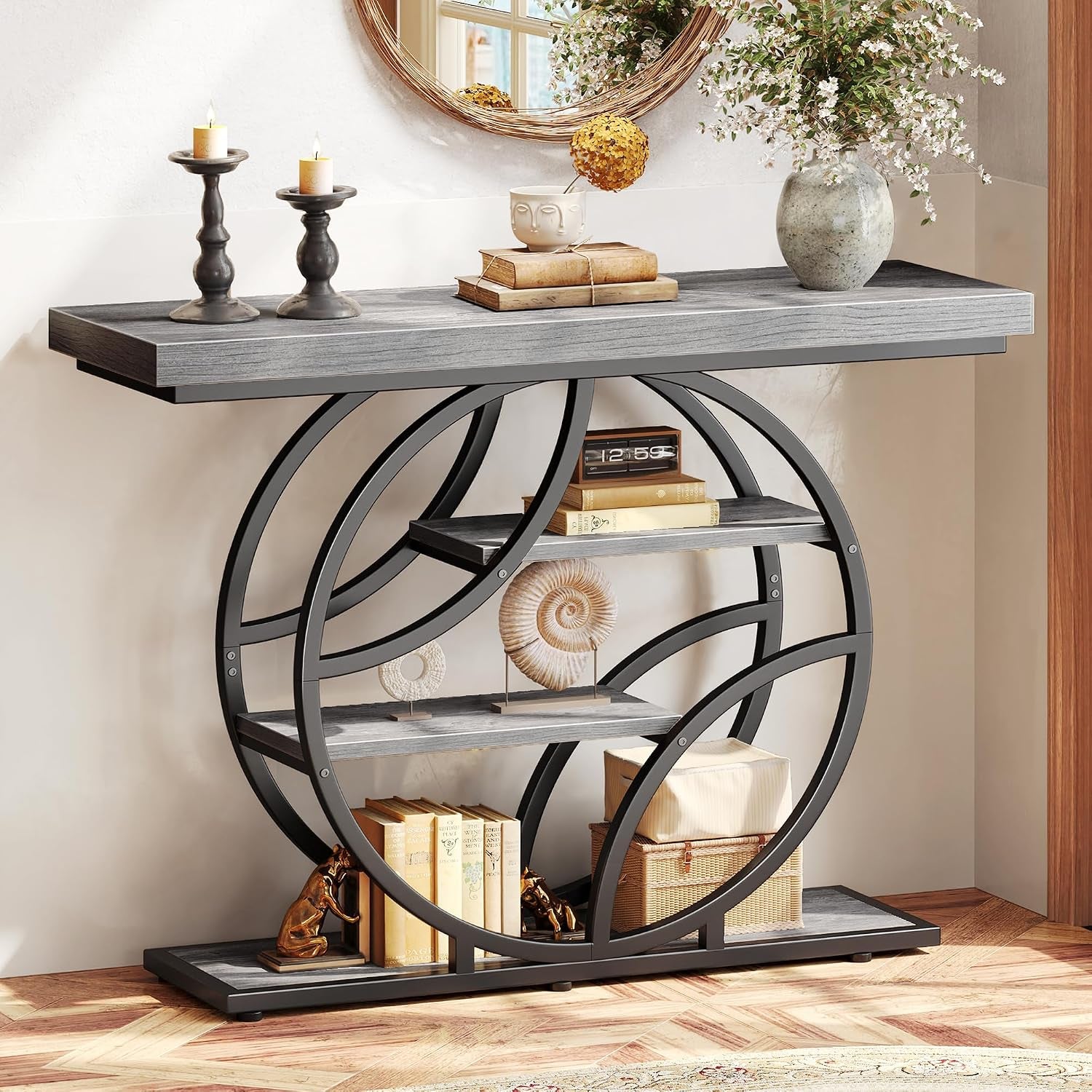 Straight-on view of the console in a gray wood finish highlighting the rounded metal frame and a shell ornament on the