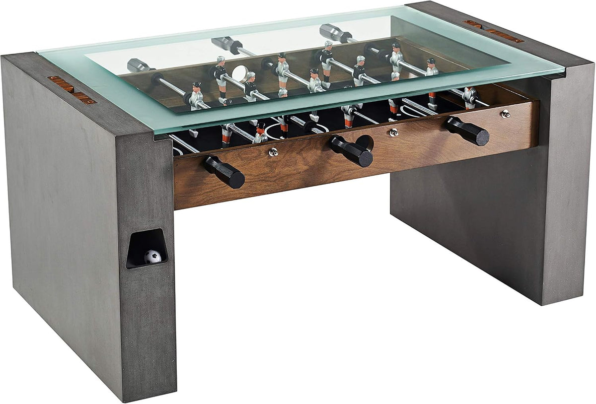 Foosball coffee table with transparent glass top, faux concrete legs and wood apron, angled front view