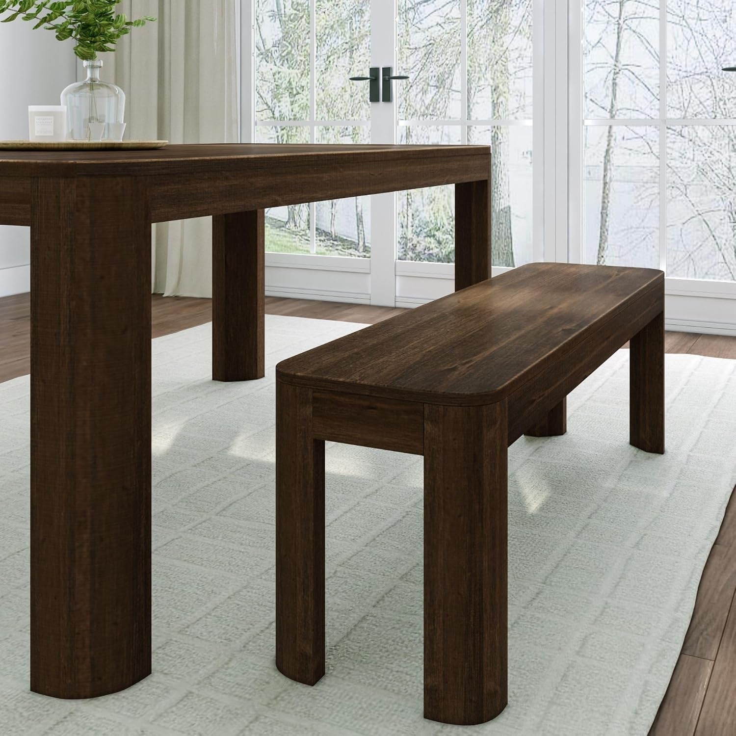 Close-up of a walnut-finished dining table and bench showing wood grain and rounded edges.