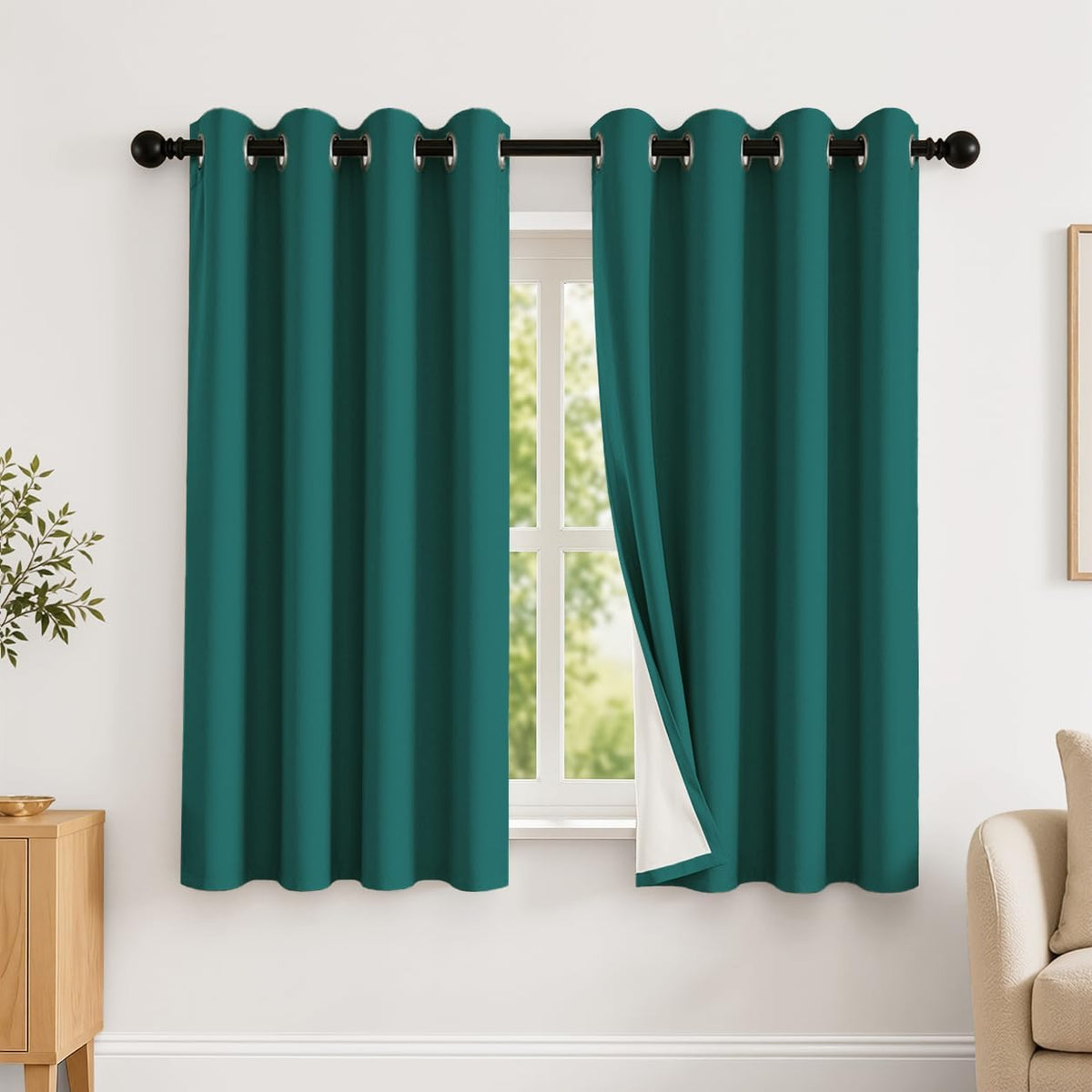 Short teal grommet curtains with one side folded back to reveal a white backing.