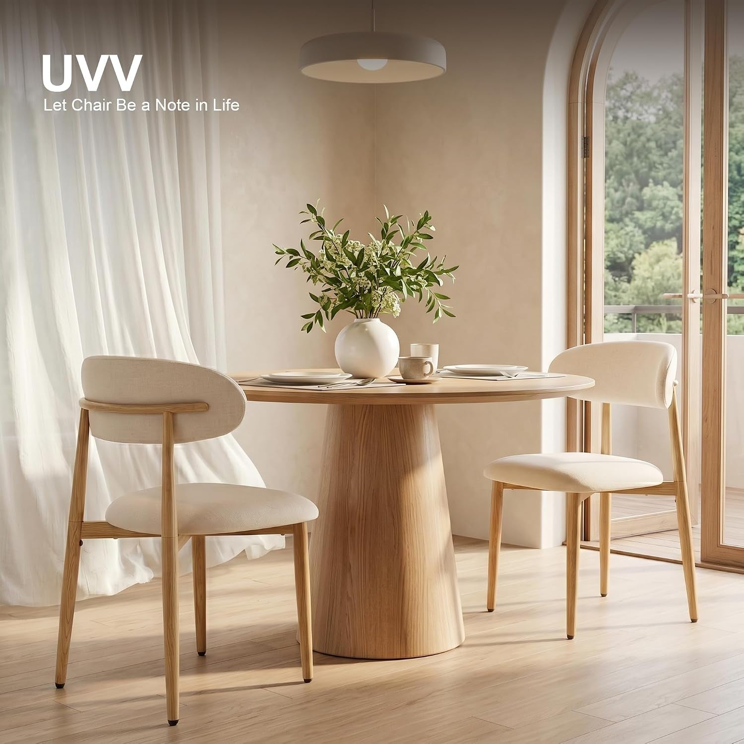 Beige upholstered dining chairs around a round wood table with pendant light and sheer curtains