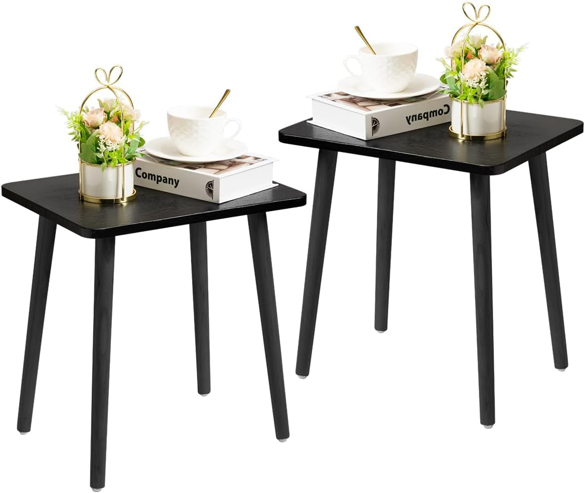 Two small black square side tables with tapered black legs shown with cup and flowers