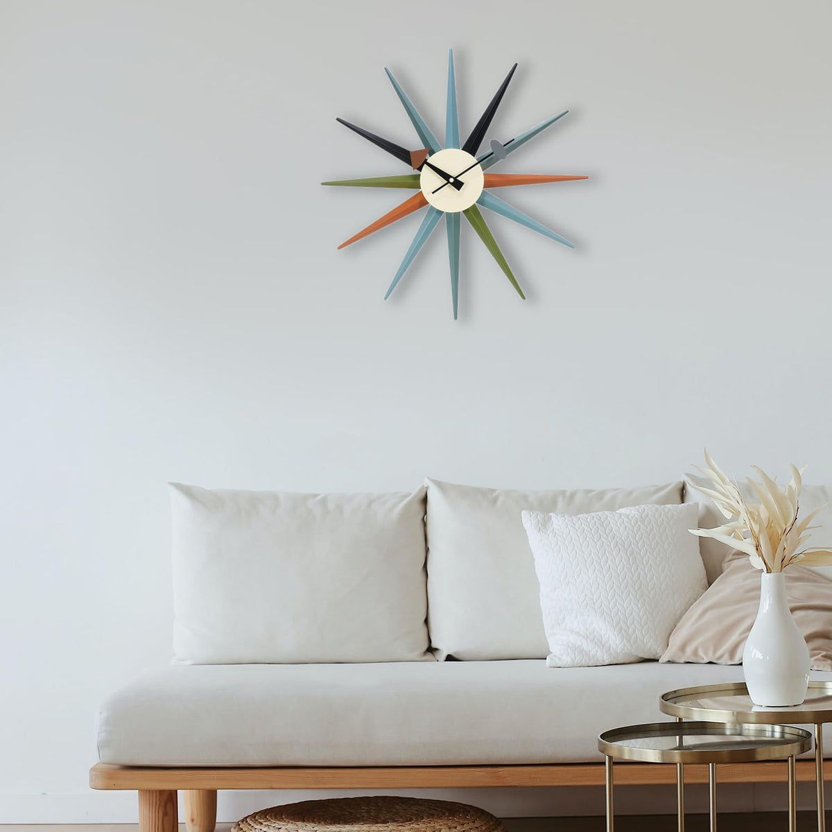 Multicolor sunburst wall clock mounted above a light sofa in a minimalist living room setting