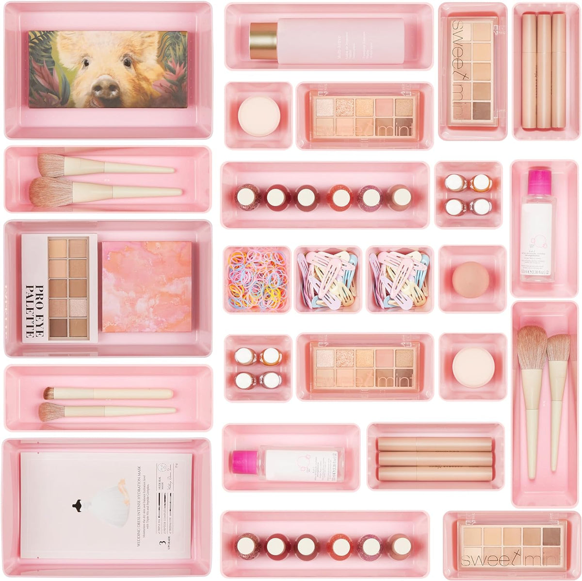 Top-down view of multiple pink plastic organizer trays filled with makeup, brushes, clips and hair ties.