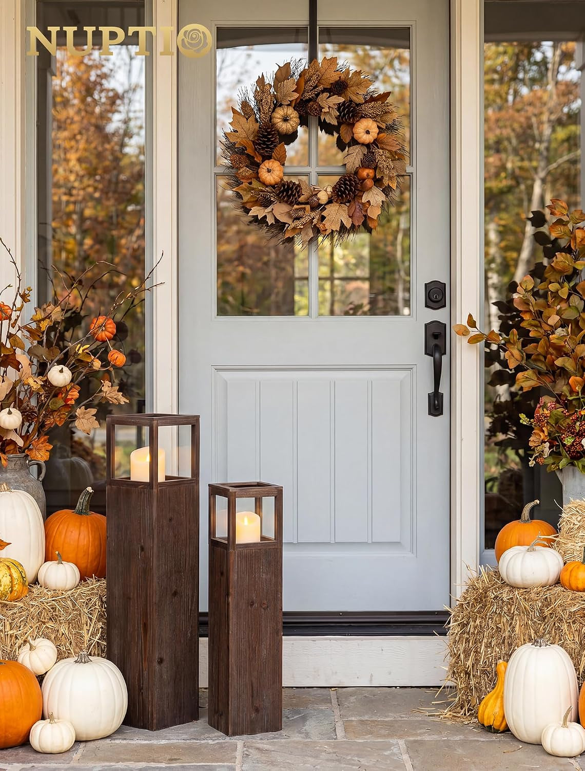 Small and medium distressed fir floor lanterns on a doorstep among fall pumpkins and hay bales