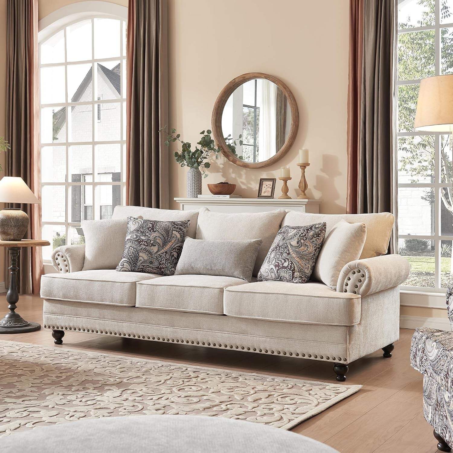 Three-seat beige chenille sofa with patterned and solid pillows in a sunlit living room.