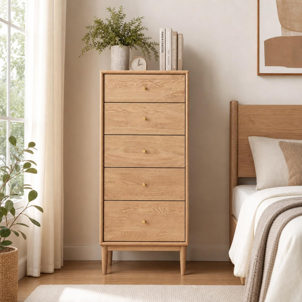 Light oak tall chest of drawers with potted plant and books on top by a window.