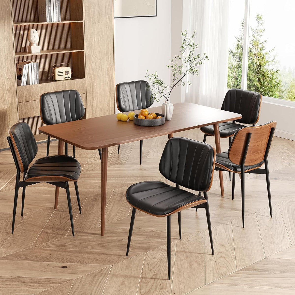 Dining table with black faux-leather chairs and walnut edge backs in a bright room.