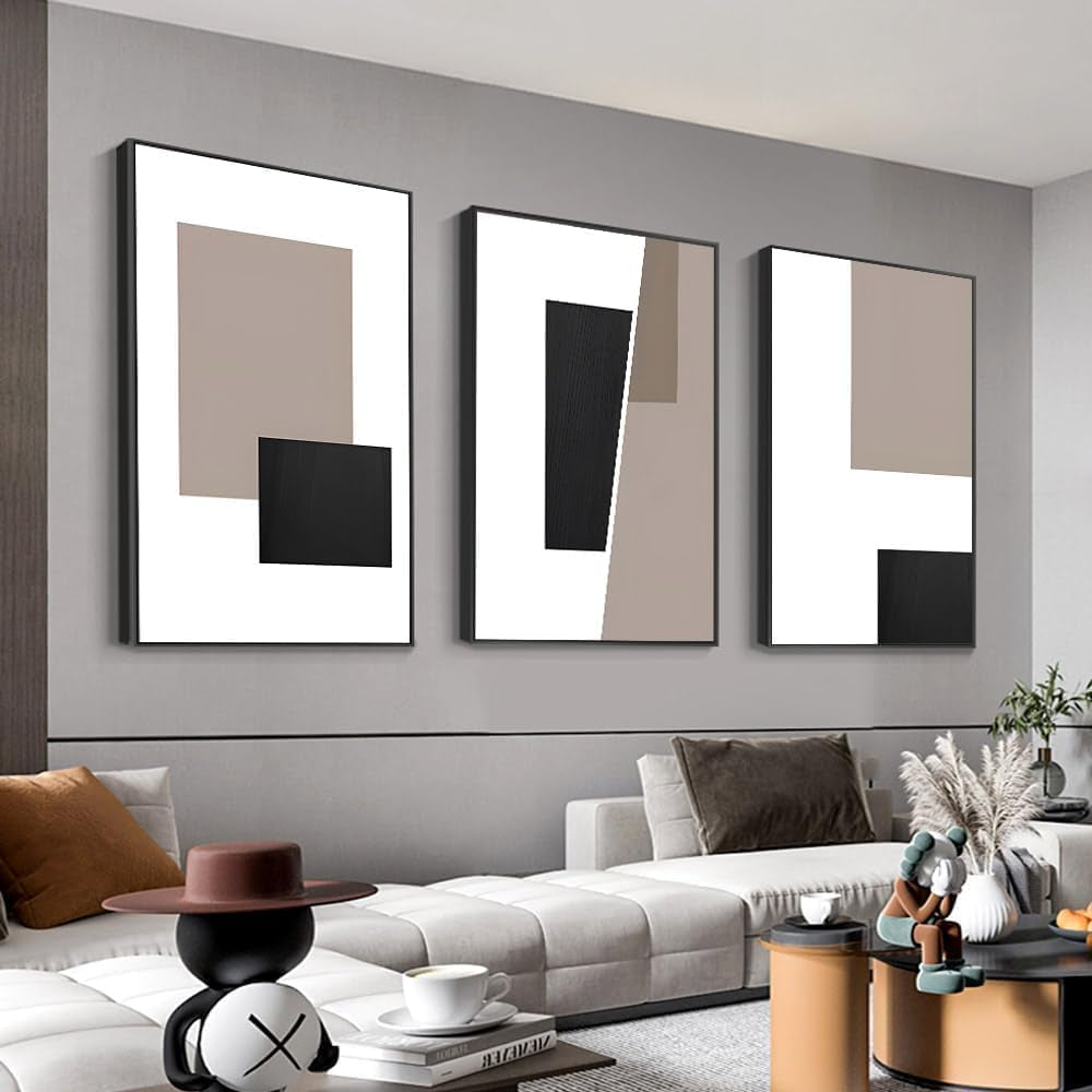 Three vibrant graffiti-style portrait canvases with bright orange, yellow and blue tones hung above a cream sofa, pampas