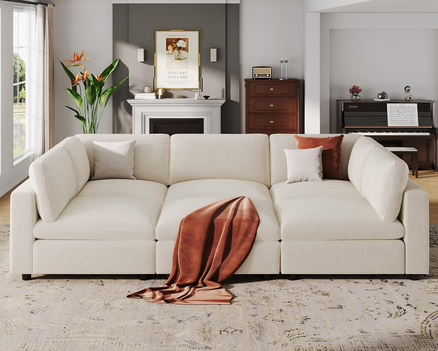 Close front view of a cream modular sectional with rust throw and pillows
