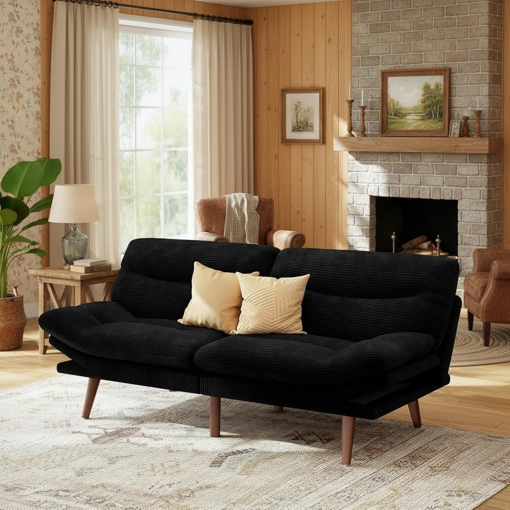 Black corduroy futon sofa angled front view in a living room with wooden legs and throw pillows