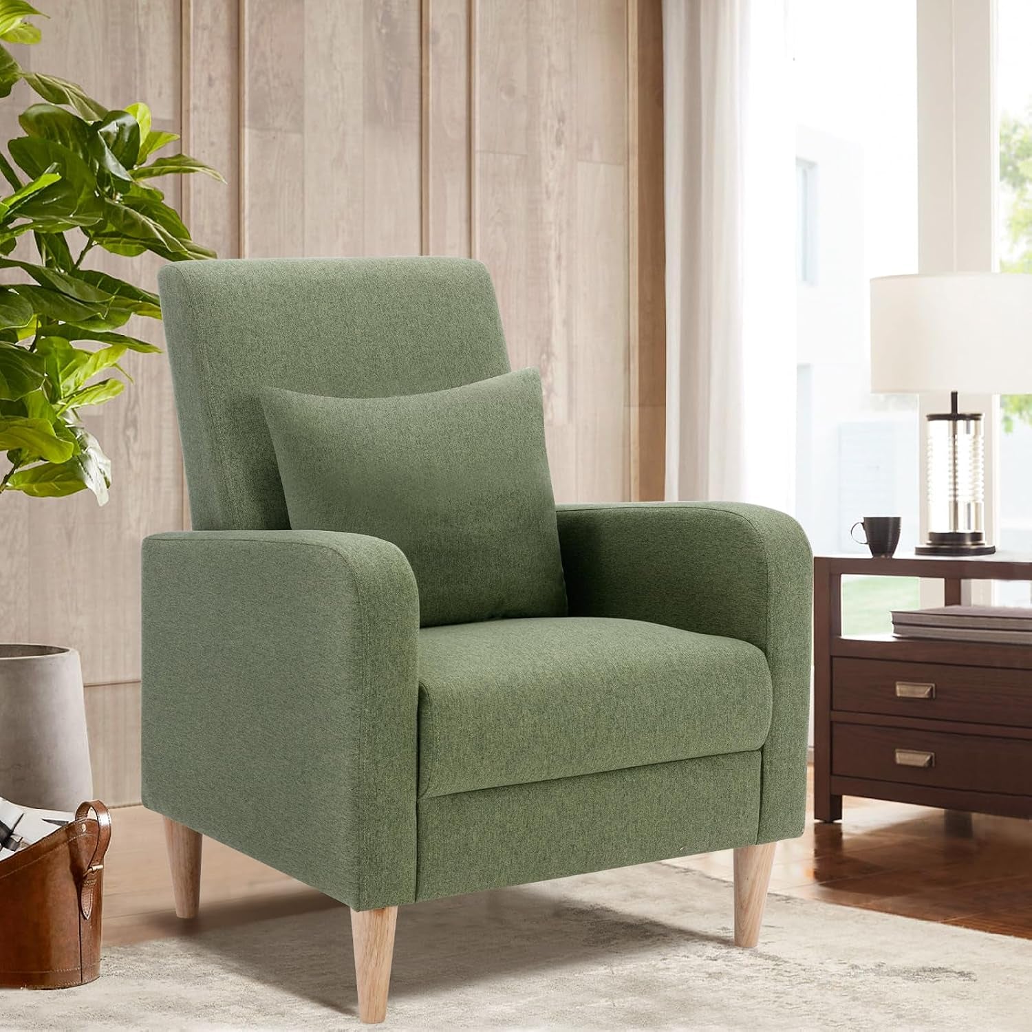 Moss green textured high-back armchair with square pillow and tapered wood legs in a sunlit room.