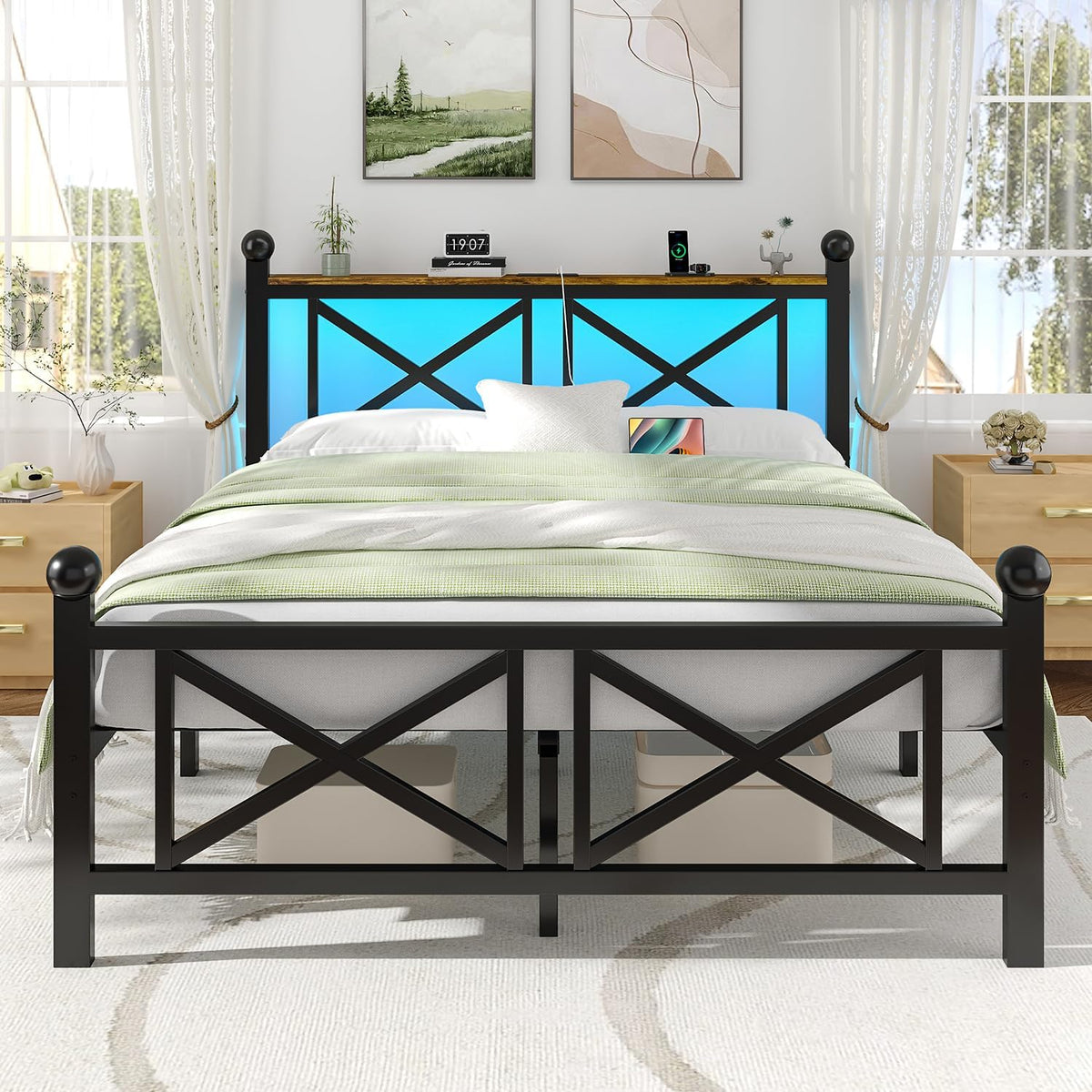 Front view of a black bed frame with X‑panel footboard and blue LED headboard in a sunlit room.