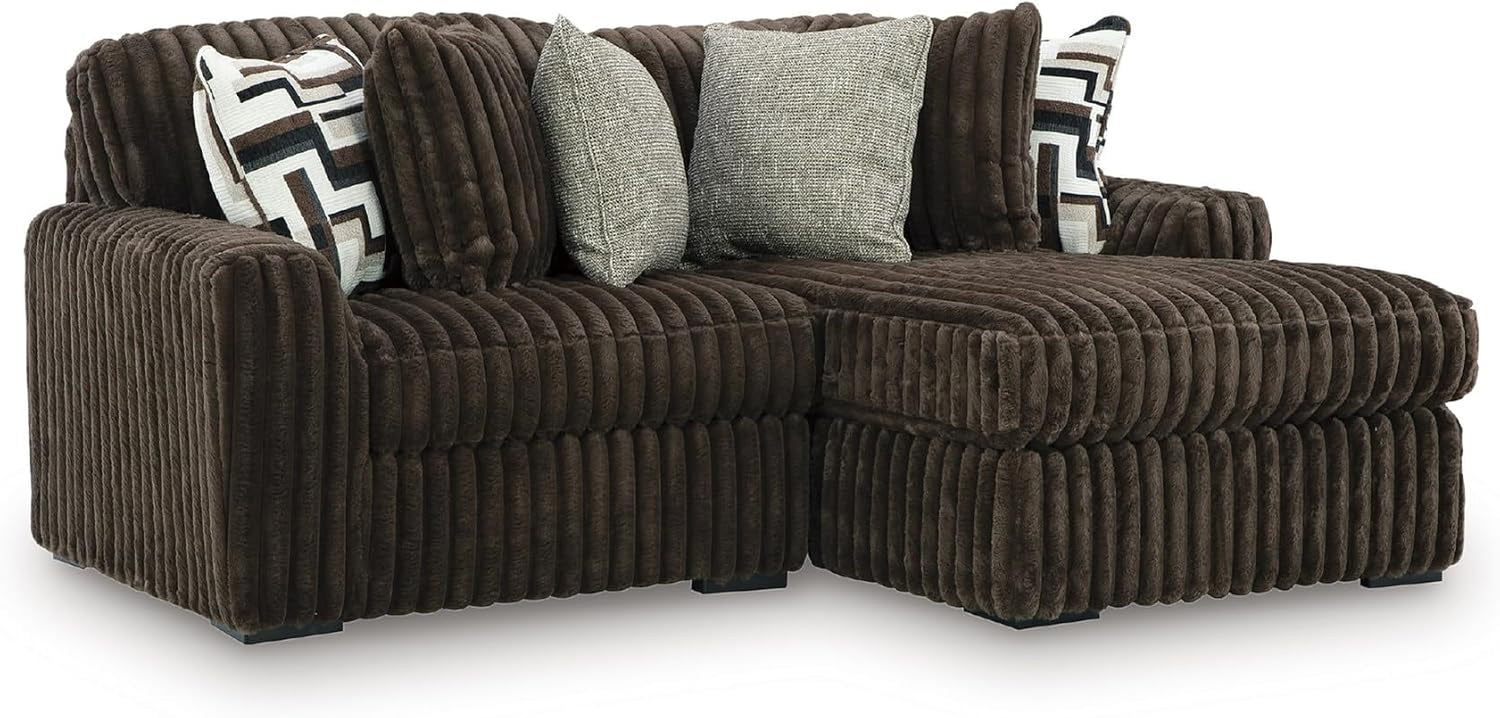Close angled side view of the chocolate brown oversized chaise section with patterned and neutral throw pillows.
