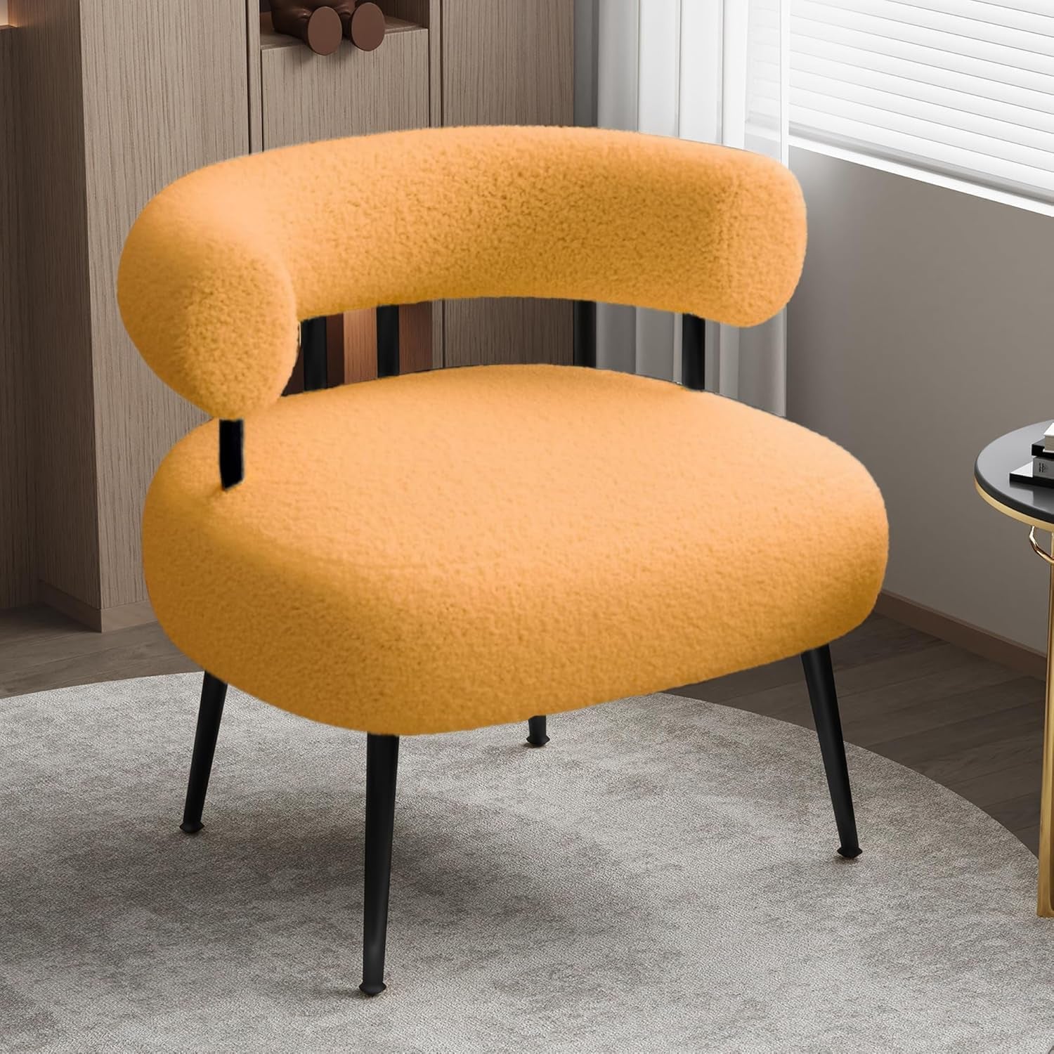 Mustard-yellow sherpa barrel chair with black legs on a round rug near a window and wood-paneled wall.