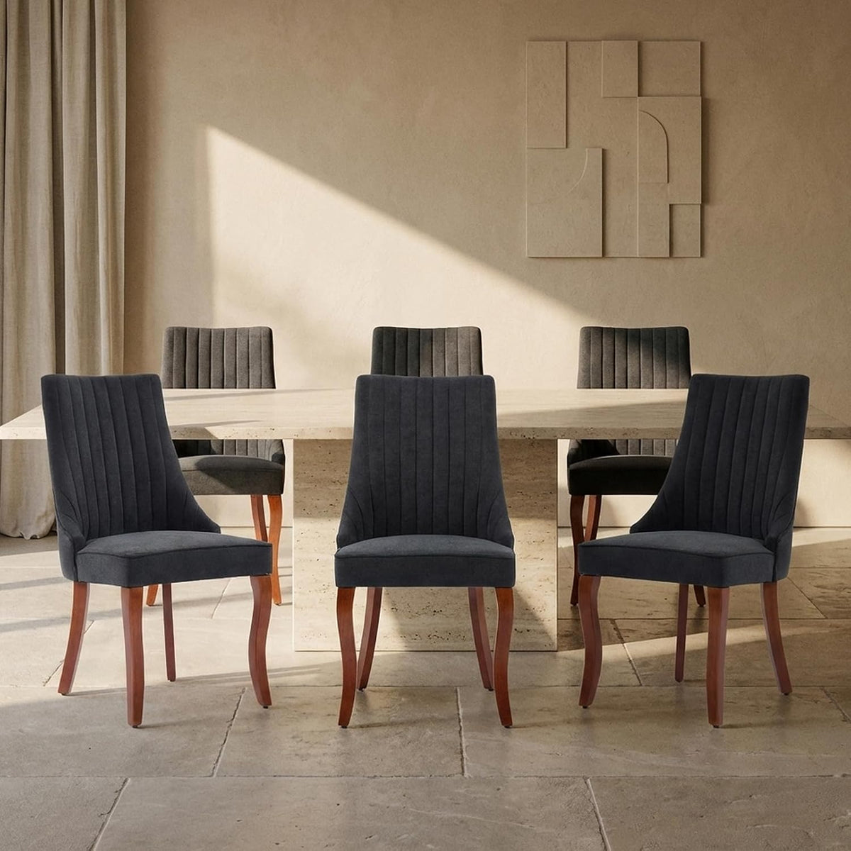 Dining room with six dark charcoal upholstered chairs with curved wood legs around a stone table.