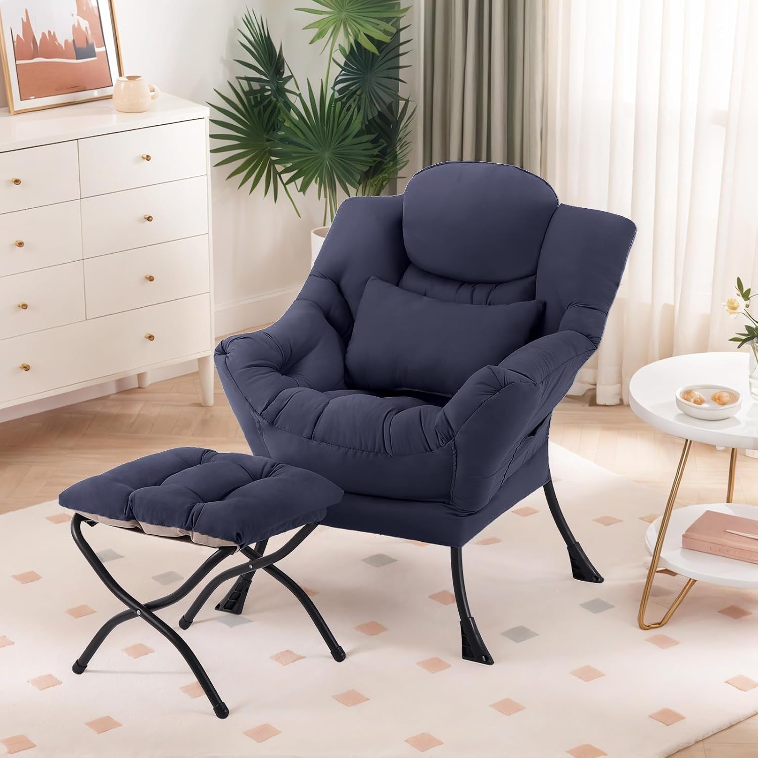 Navy blue cushioned lounge chair with matching ottoman and lumbar pillow in a bright living room.