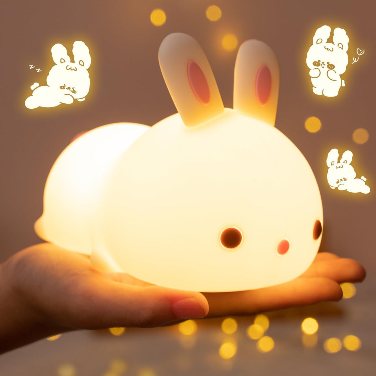 Glowing bunny silicone night light held in a hand showing warm front-side close-up view