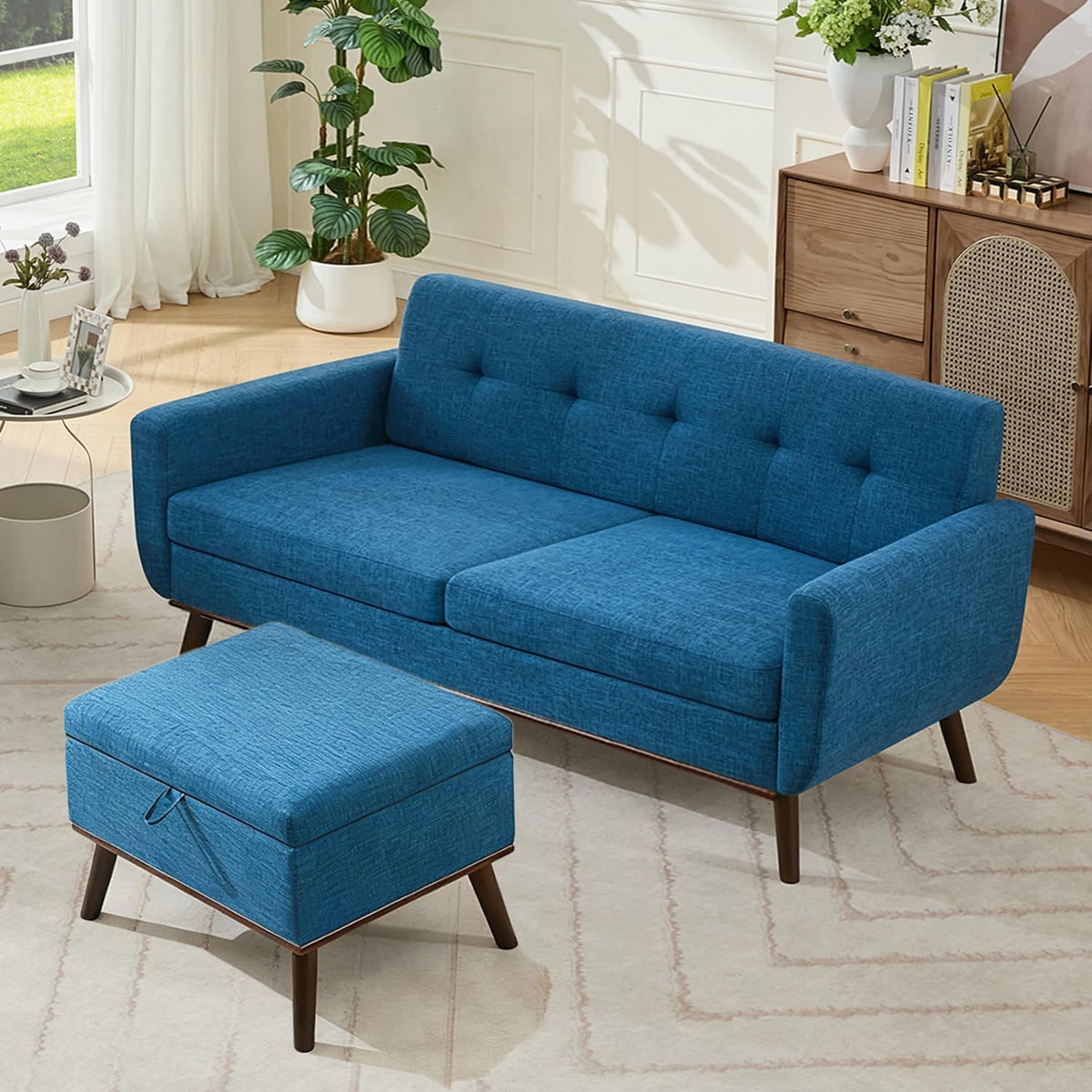 Elevated three-quarter view of a blue tufted loveseat with matching ottoman and wood legs in a bright room