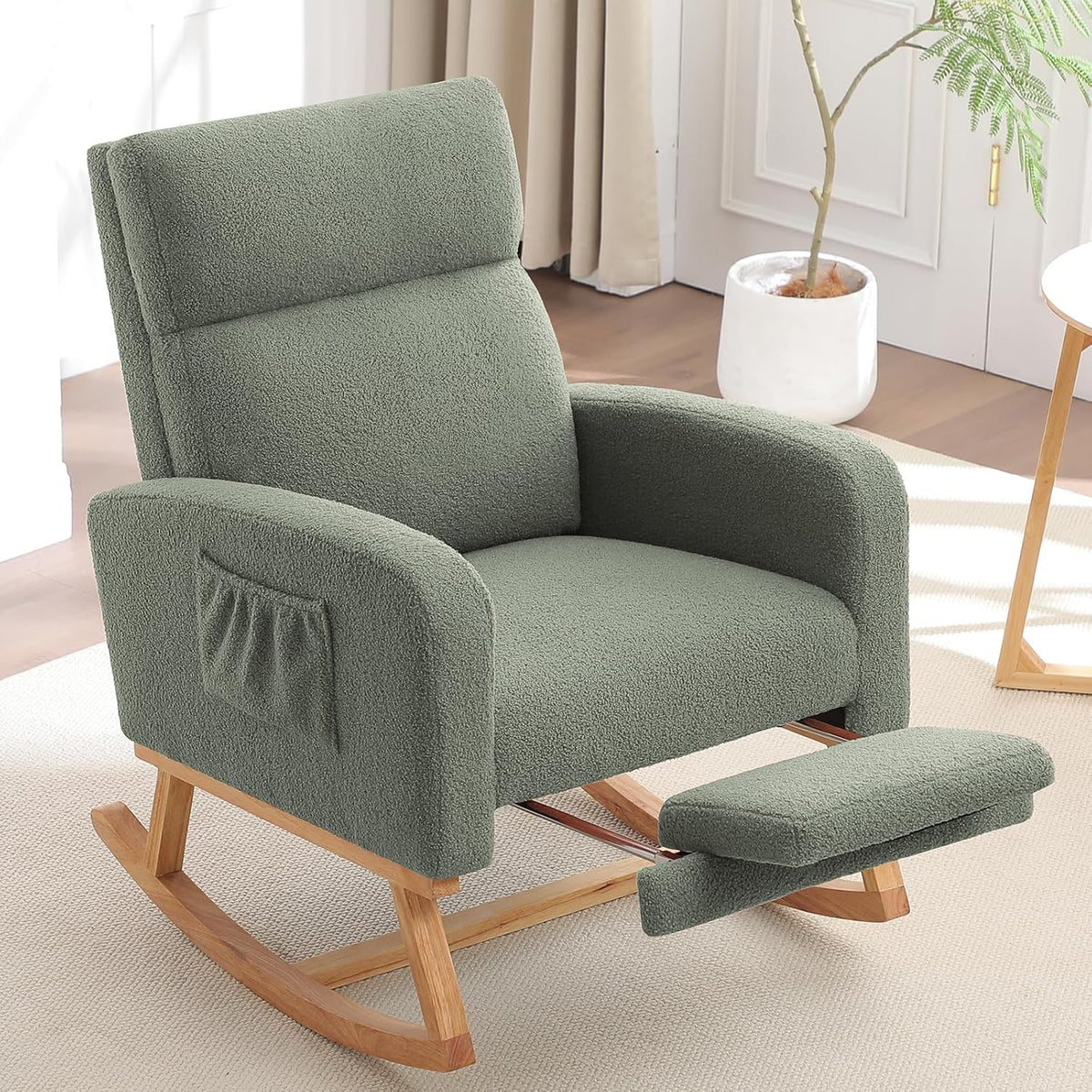 Sage green cushioned rocking chair with padded footrest and wooden runners beside a plant