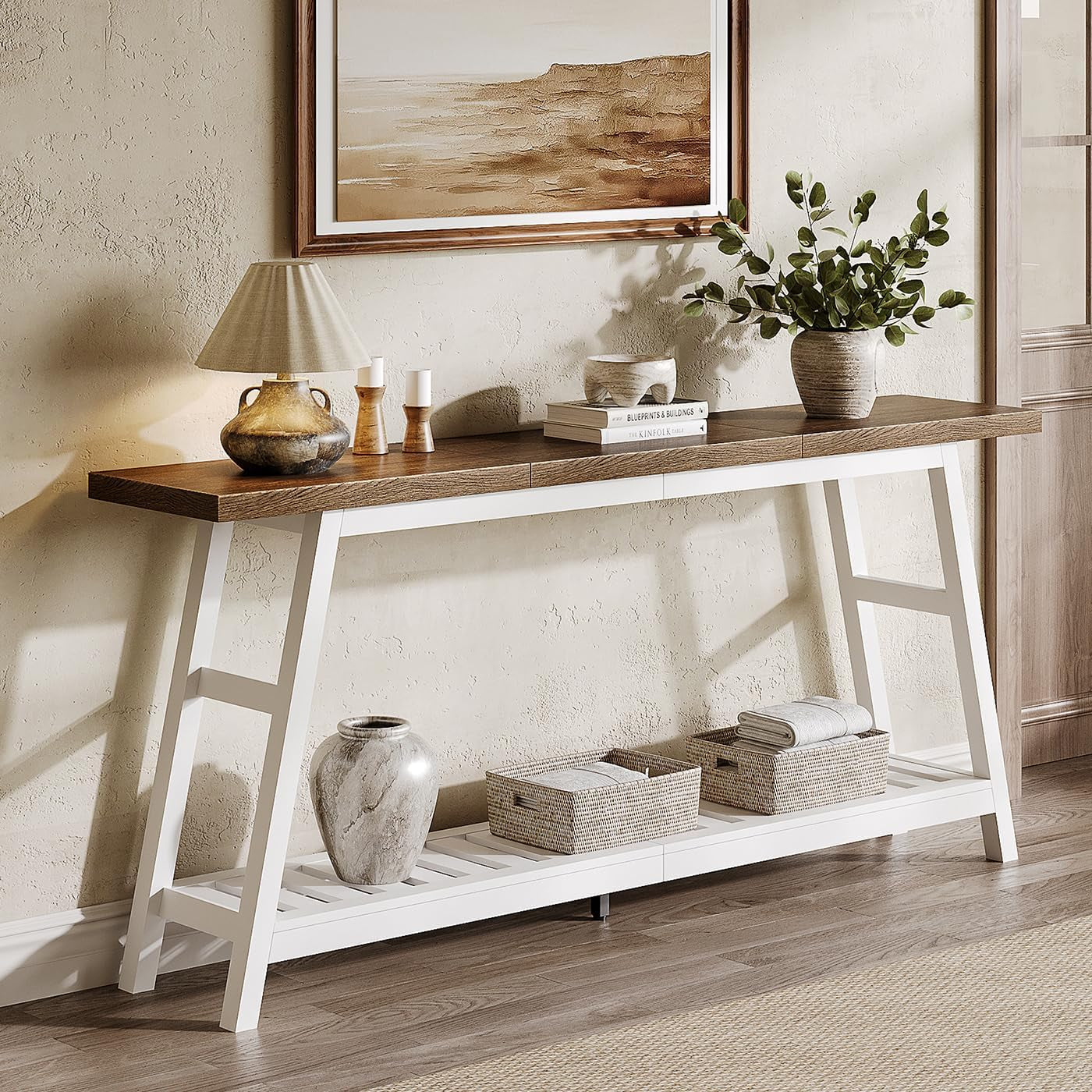 Right-side angled view of a narrow console with white trestle legs, dark wood top, tabletop books and a potted green plant.