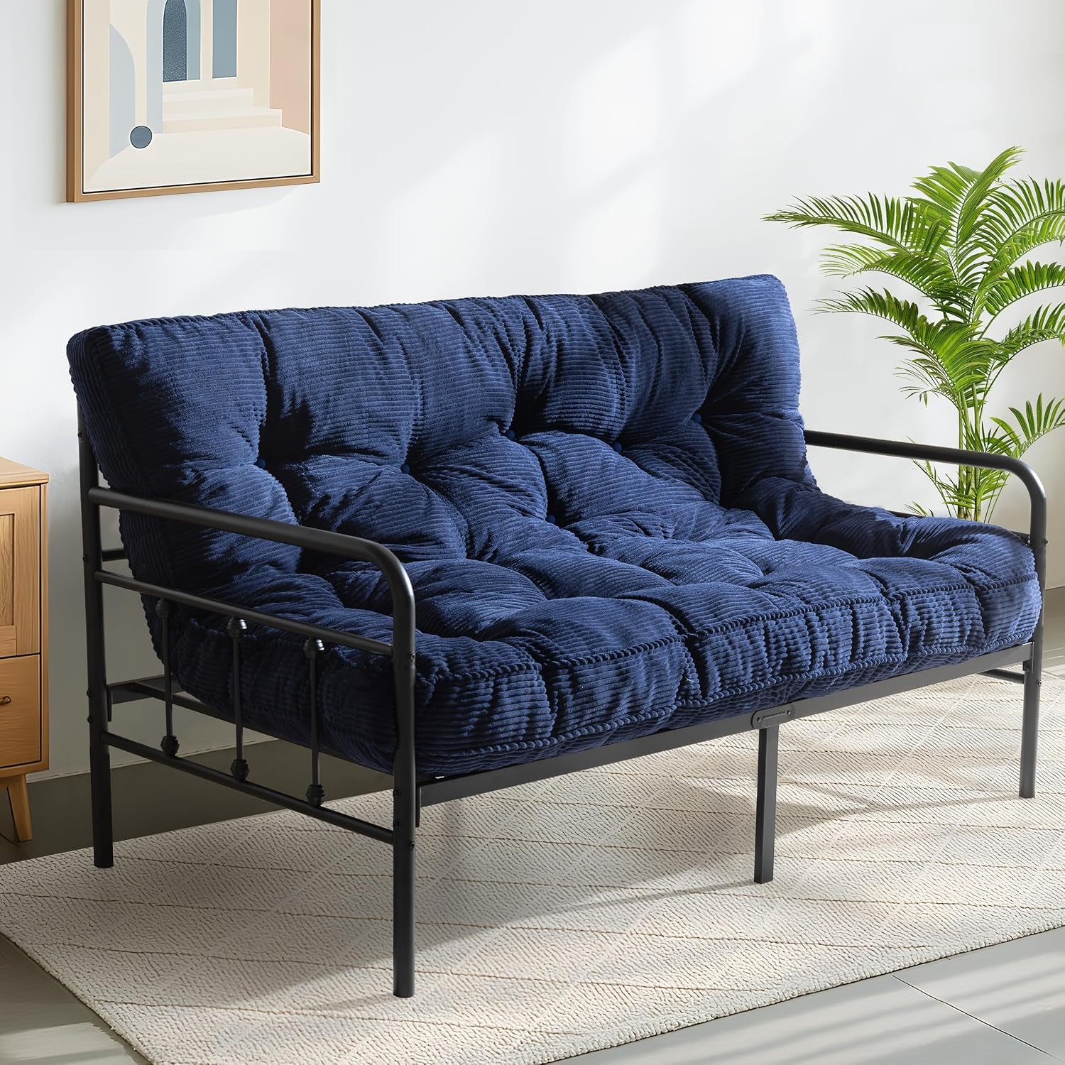 Deep navy ribbed futon mattress on a black metal frame showing tufted seat and back profiles.