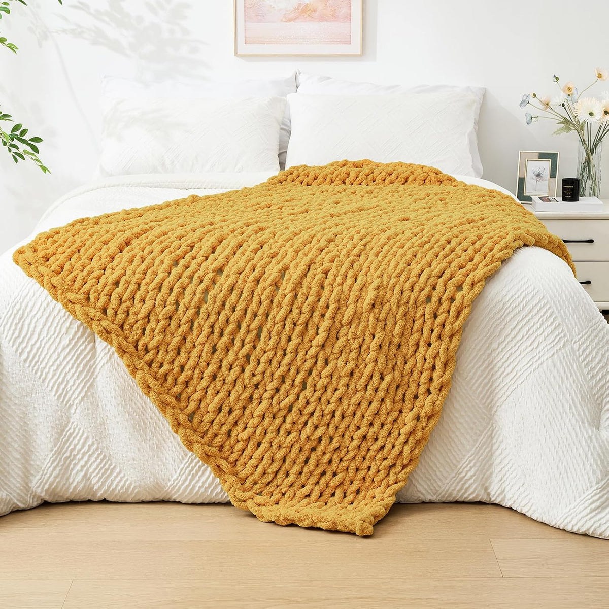 Mustard-yellow chunky knit throw spread over a white quilt on a bed