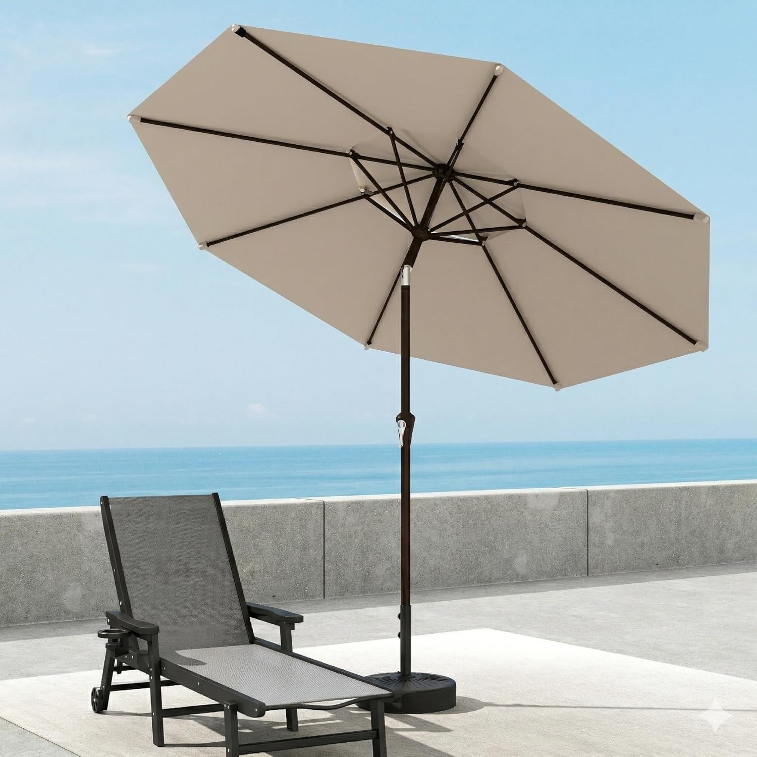 Beige 10ft patio umbrella open beside a lounge chair on a seaside terrace.