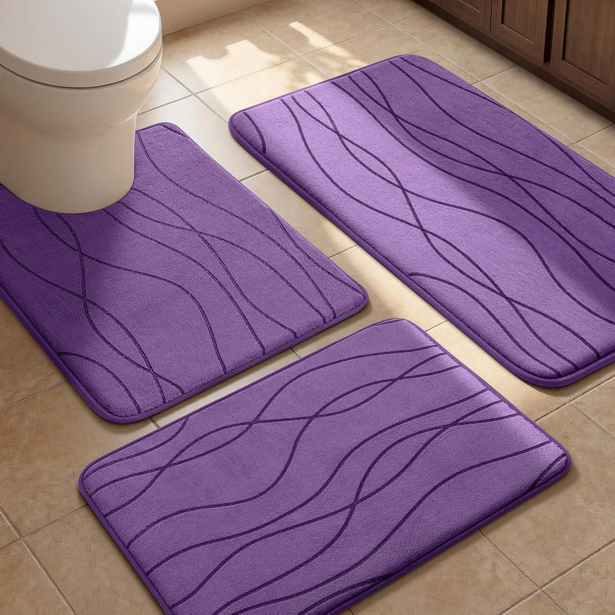 Three purple bath rugs on a tiled floor with a toilet visible at the top left.