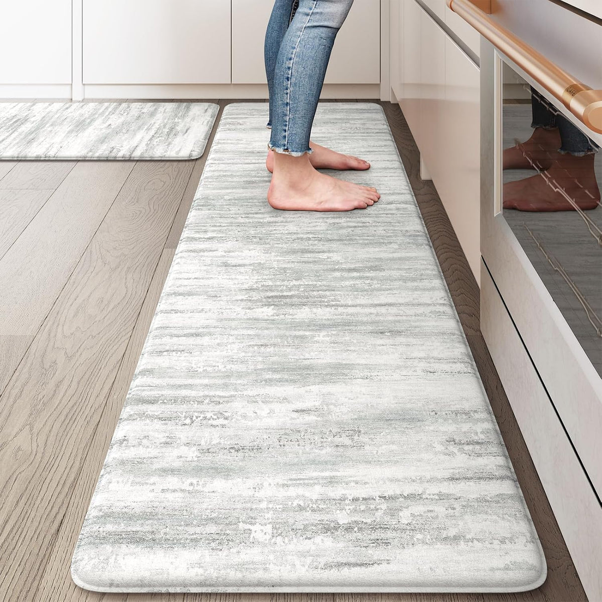 Top-down view of a light-gray abstract kitchen runner with bare feet standing at a counter.