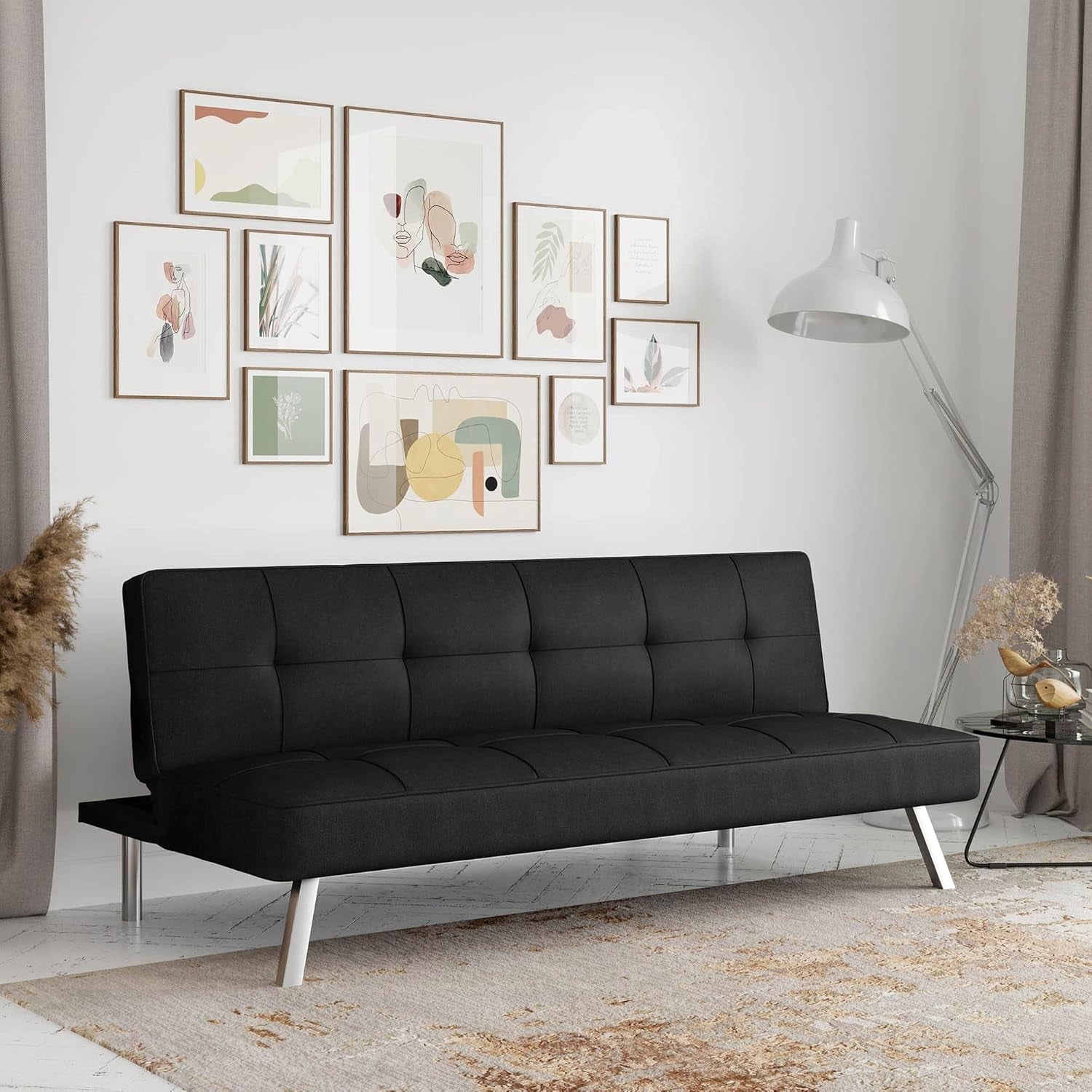 Tufted black convertible futon sofa with chrome angled legs in the same staged living room.