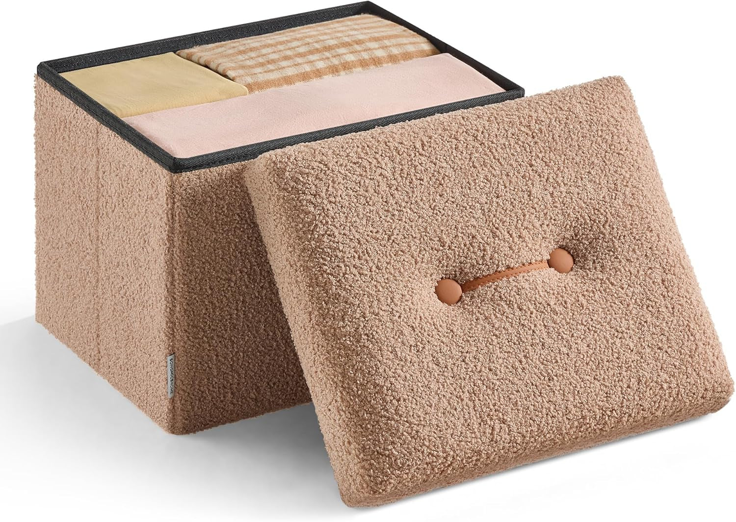 Fuzzy beige storage ottoman with its lid leaned forward and folded textiles visible inside