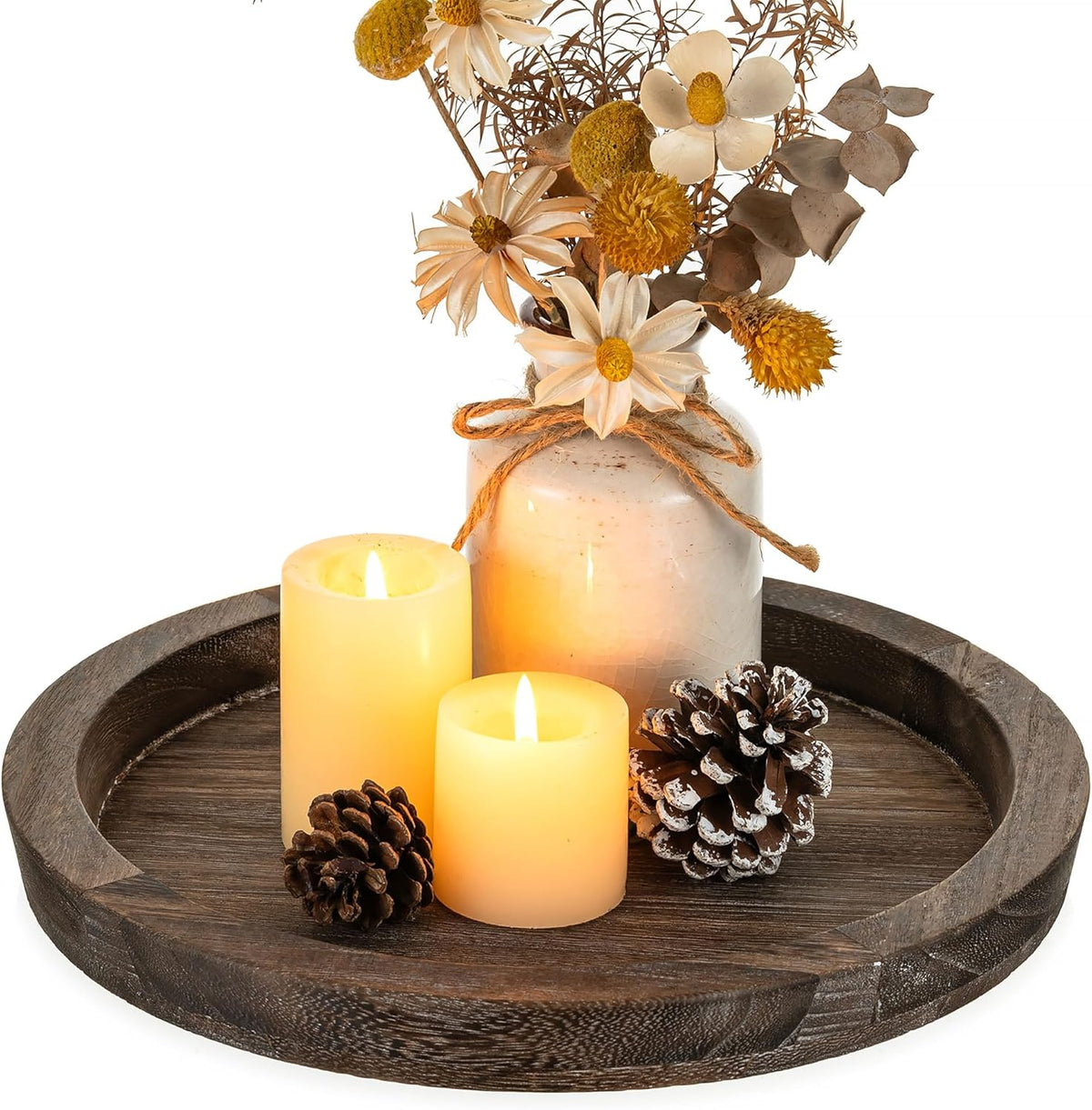 Dark brown round wooden tray with pillar candles and a small ceramic vase, angled close-up