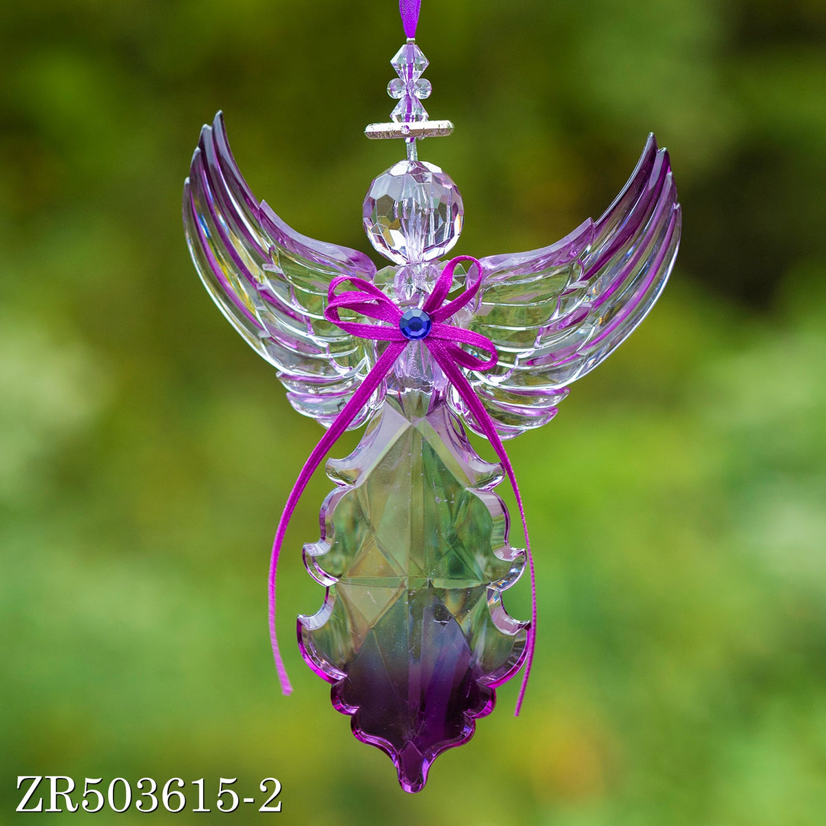 Front view of a clear angel ornament with raised wings and long purple ribbon tails hanging beside its body.