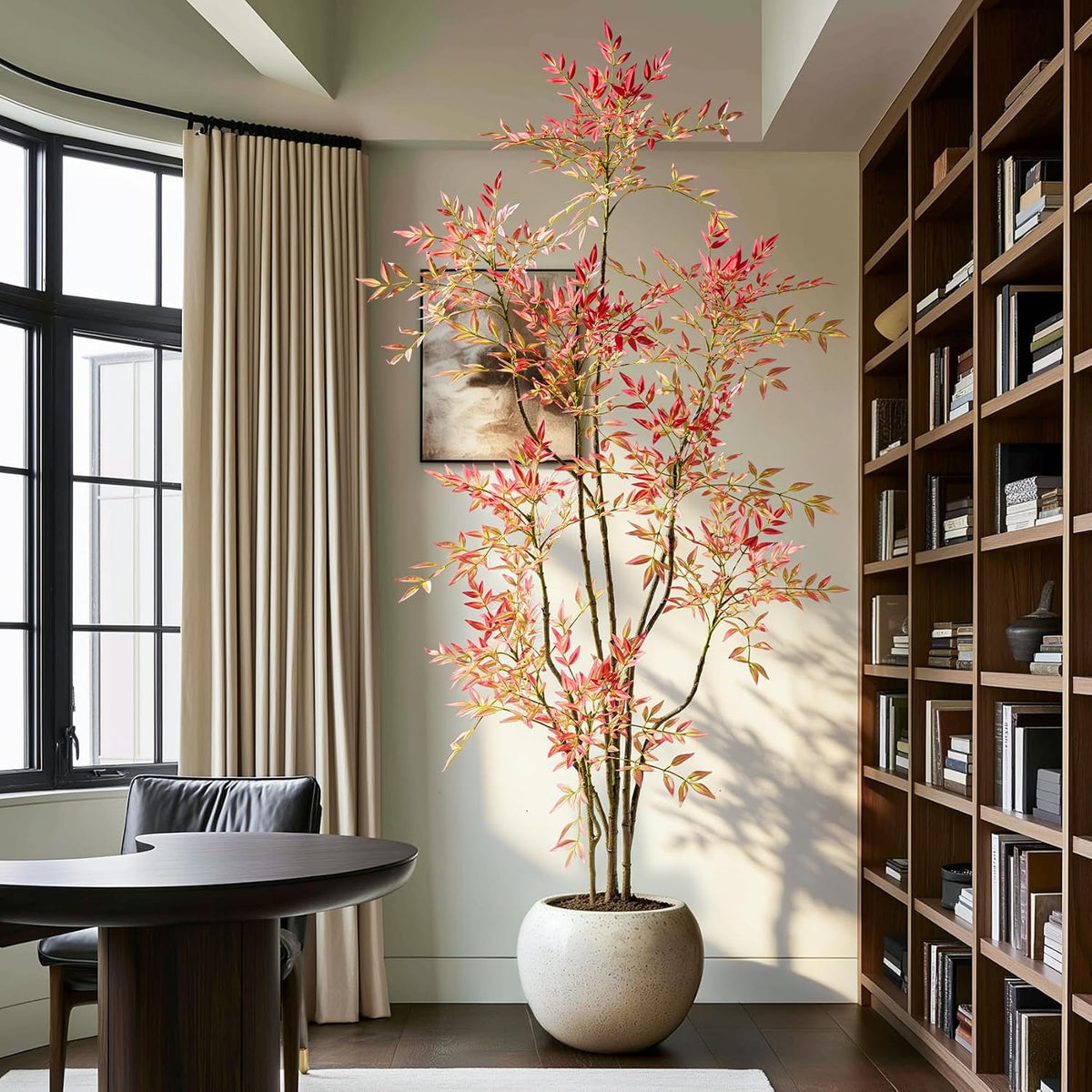 Faux Nandina with pinkish-red leaves in a round speckled planter next to a bookcase in a study